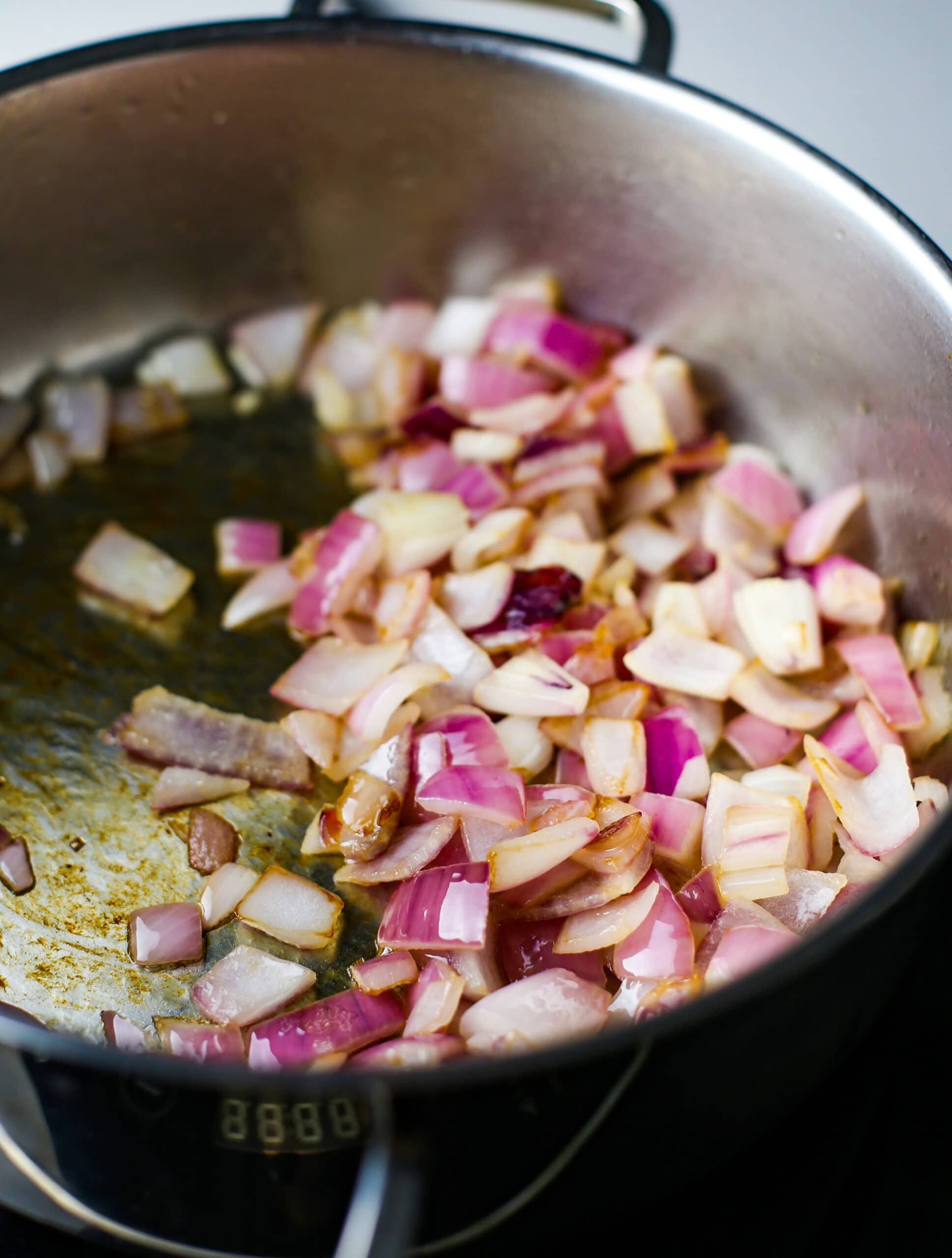 Sauteed chopped red onions in a saucepan.