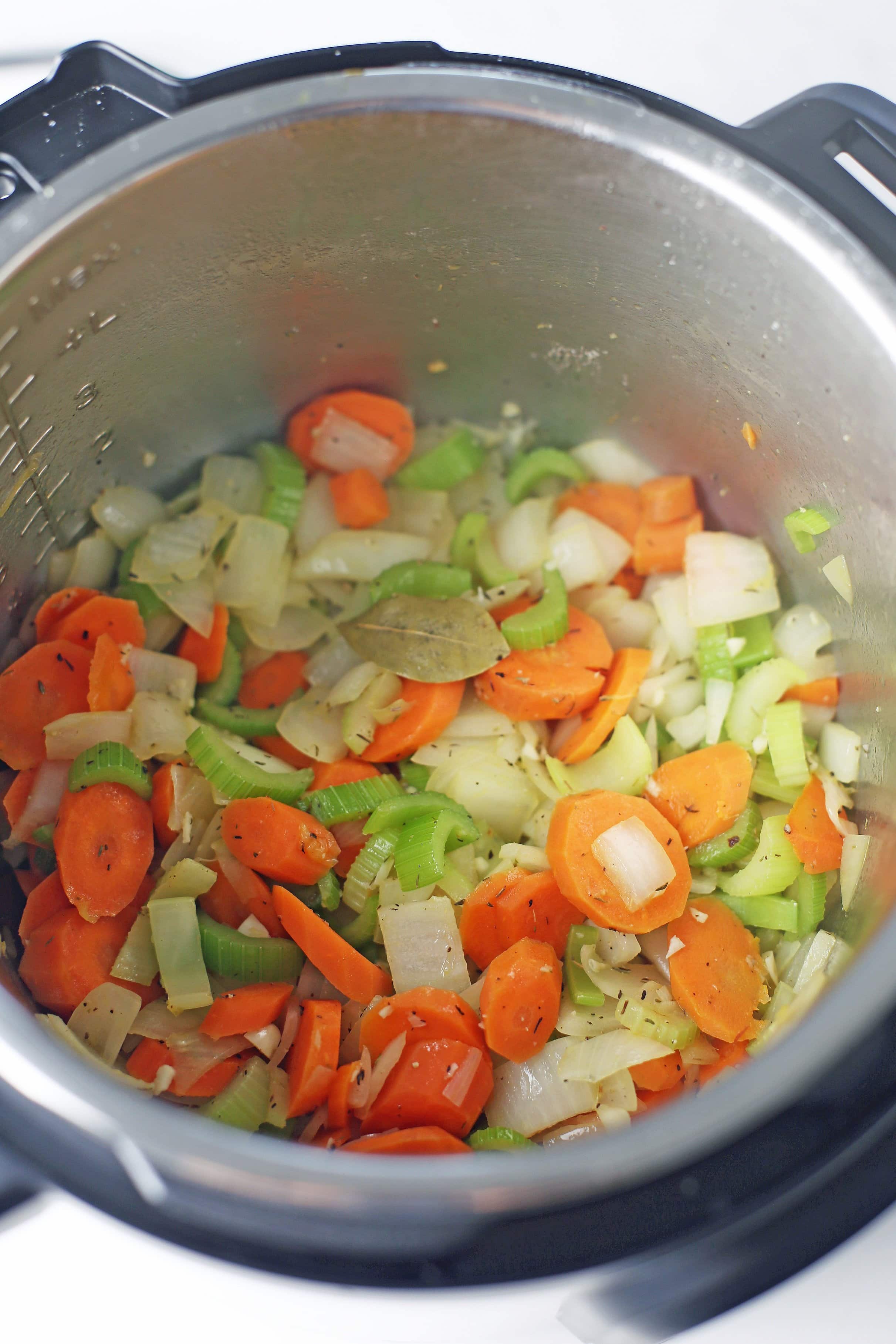 Sautéed carrots, celery, onion, and garlic with dried thyme and bay leaves in the Instant Pot.