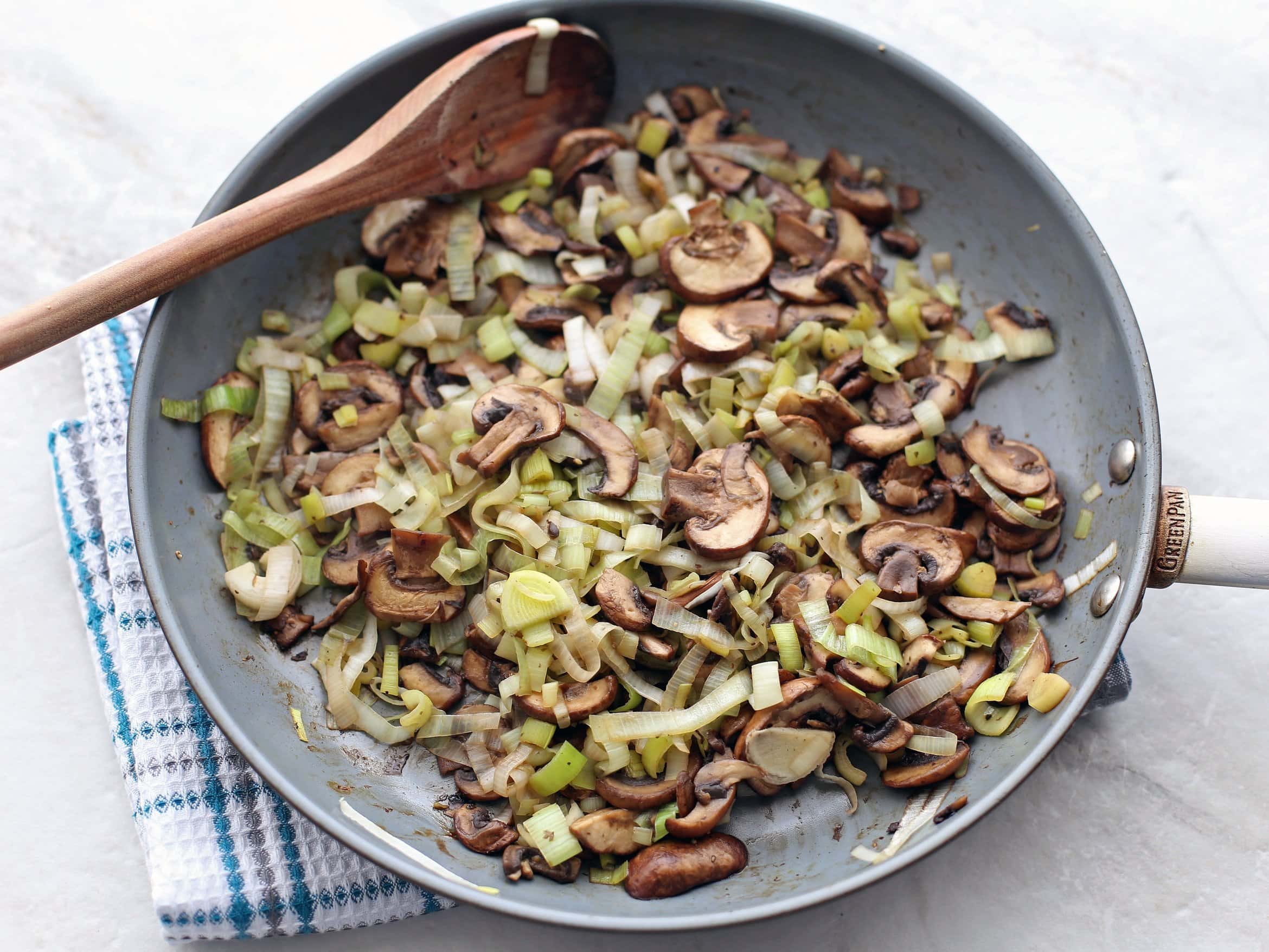 Sautéed leeks and muffins in a frying pan.