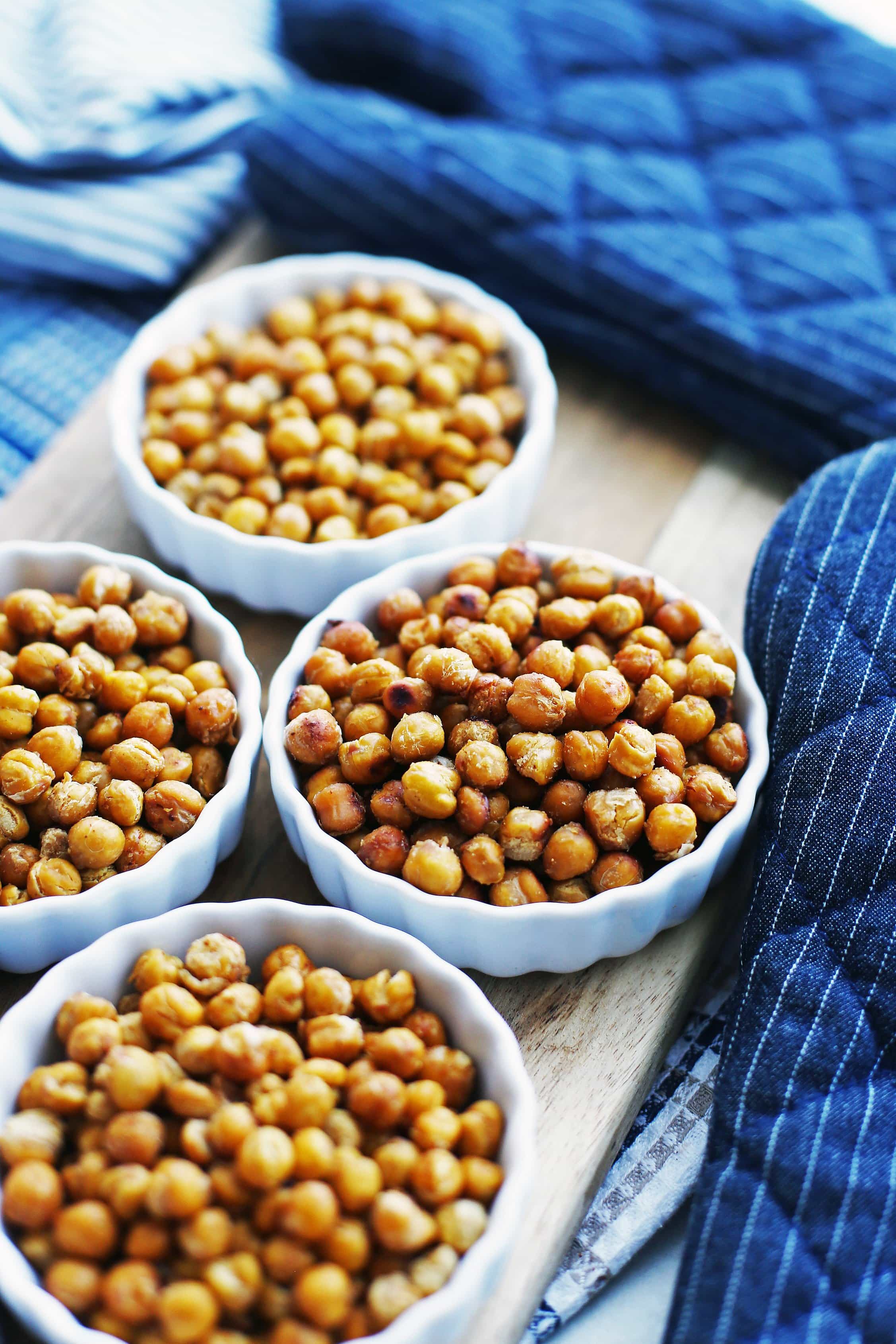 Honey garlic roasted chickpeas in a mini porcelain tart pan surrounded by three other tart pans containing assorted seasoned roasted chickpeas.