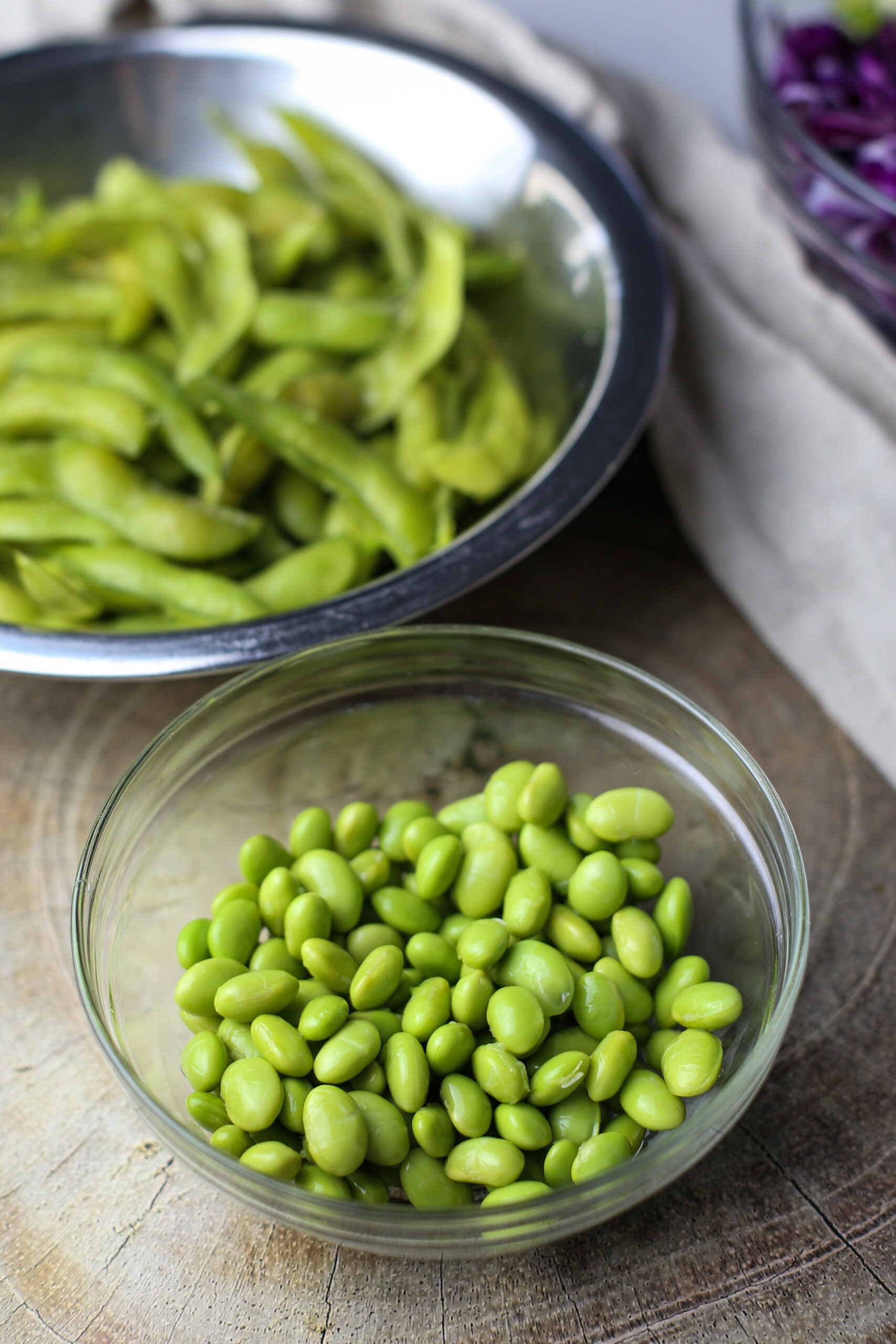 Shelled cooked edamame in a glass bowl.