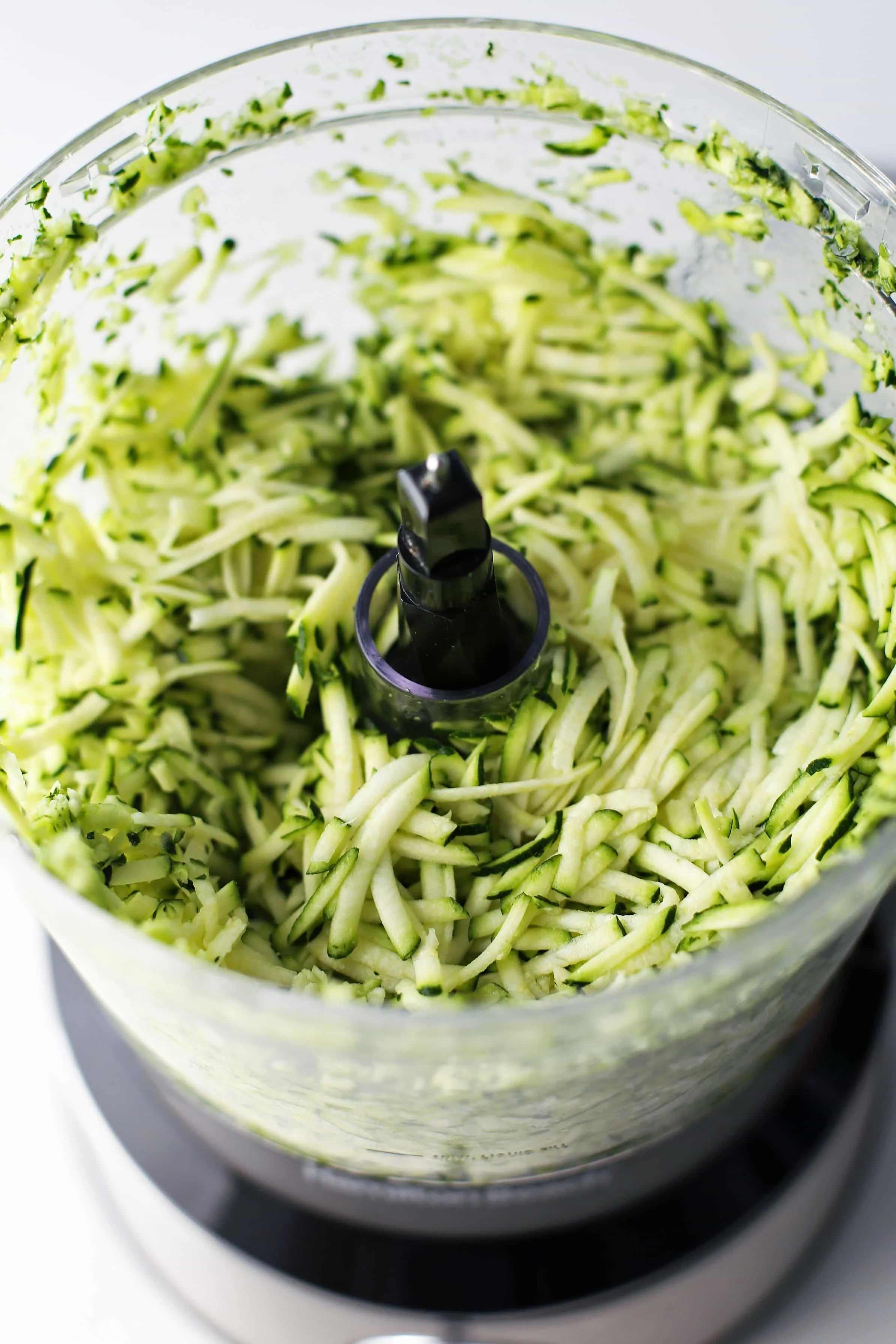 Shredded zucchini a food processor container.