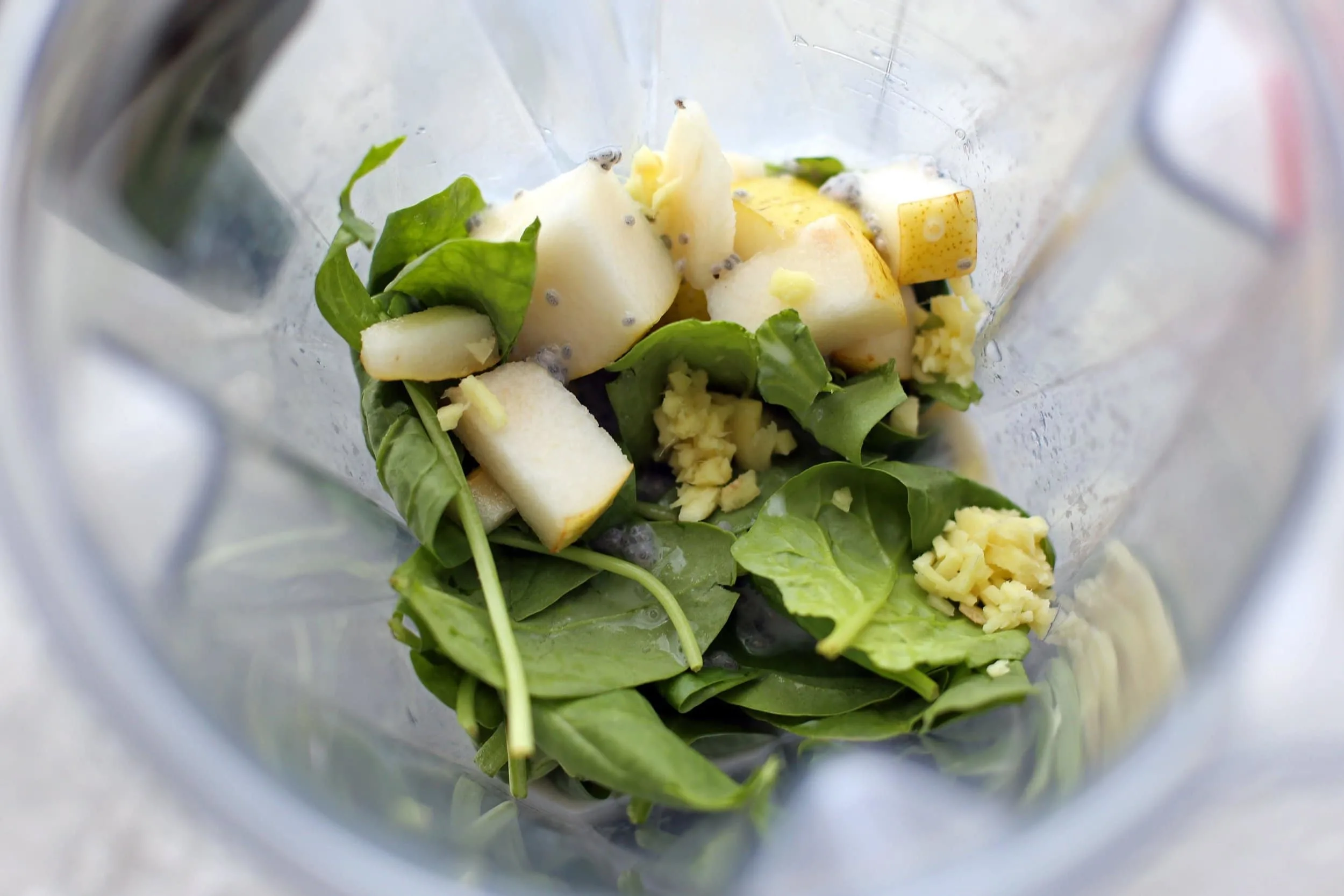 Spinach, pear, ginger root, chia seeds, almond milk, and maple syrup in a blender.