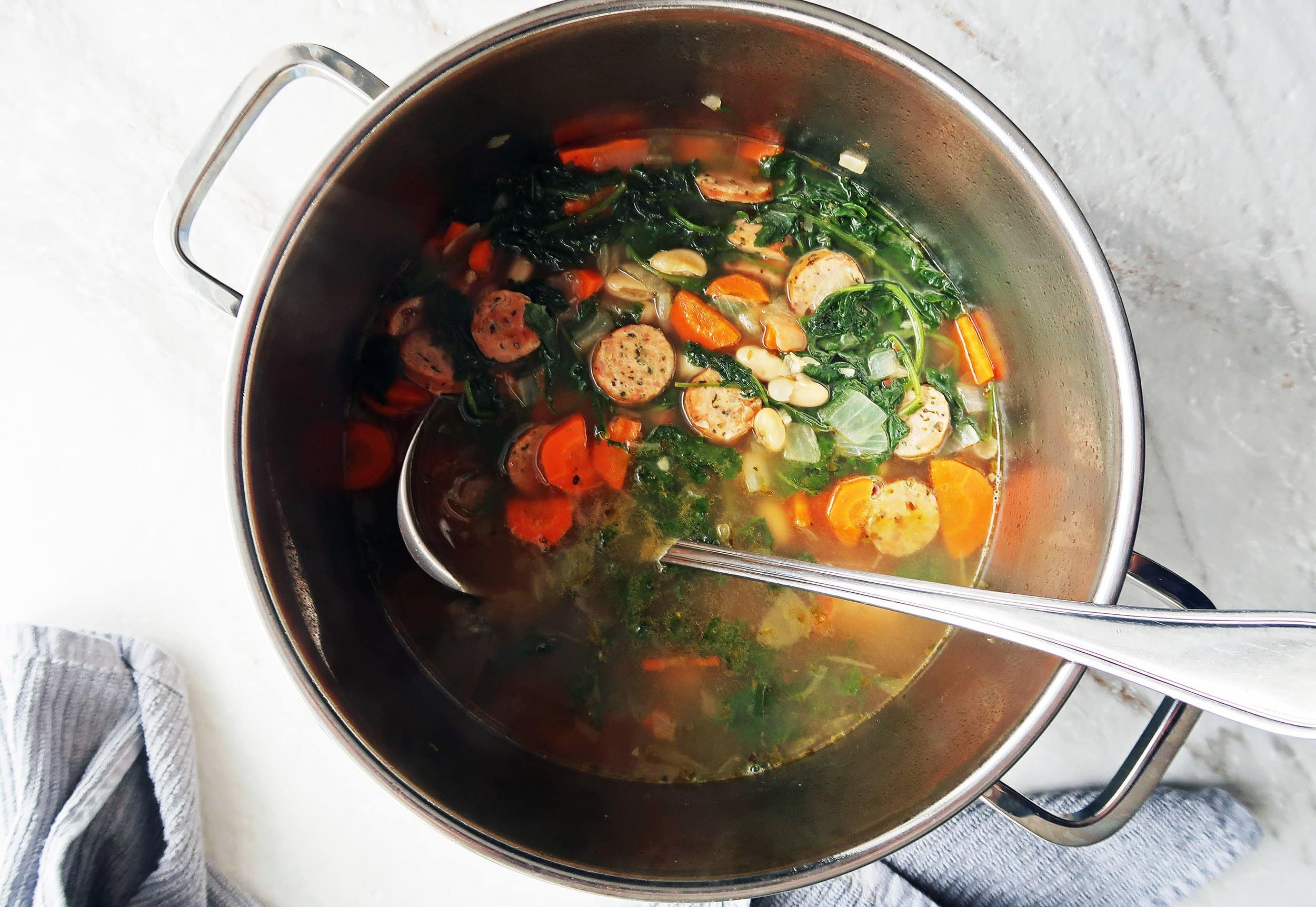 Soup ingredients in a pot with a ladle.