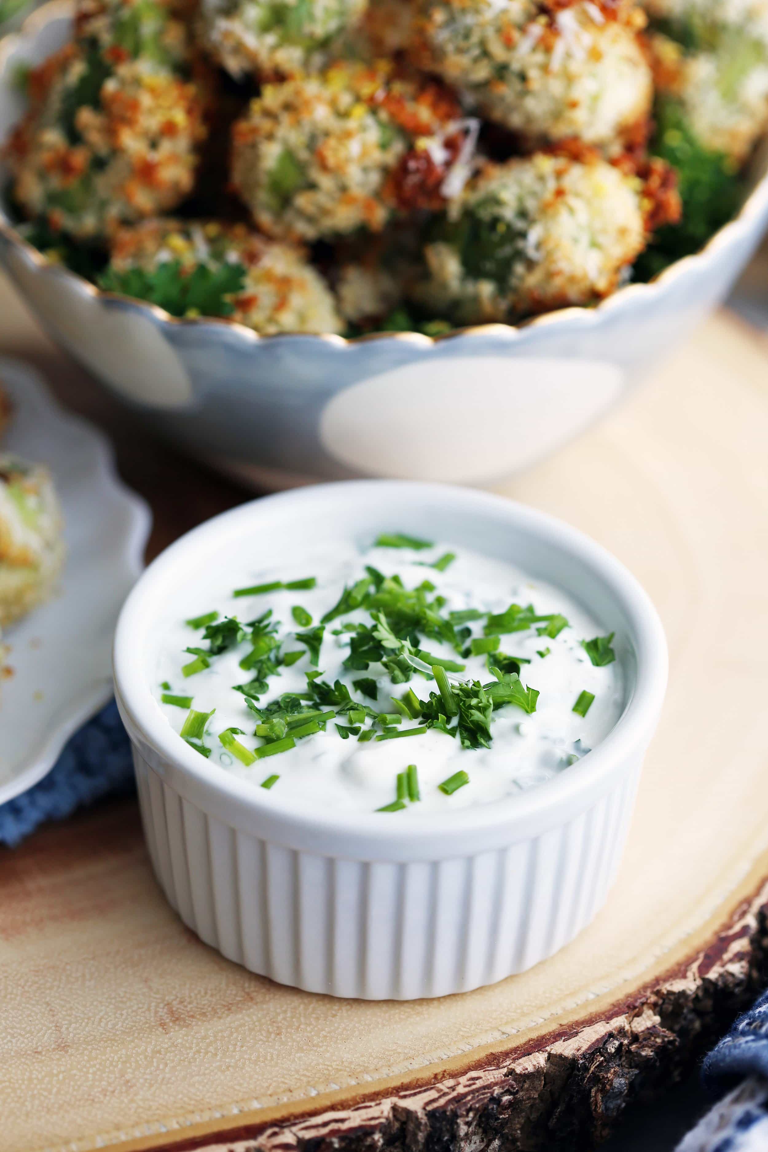 Sour cream herb dip in a white ramekin on wooden platter.