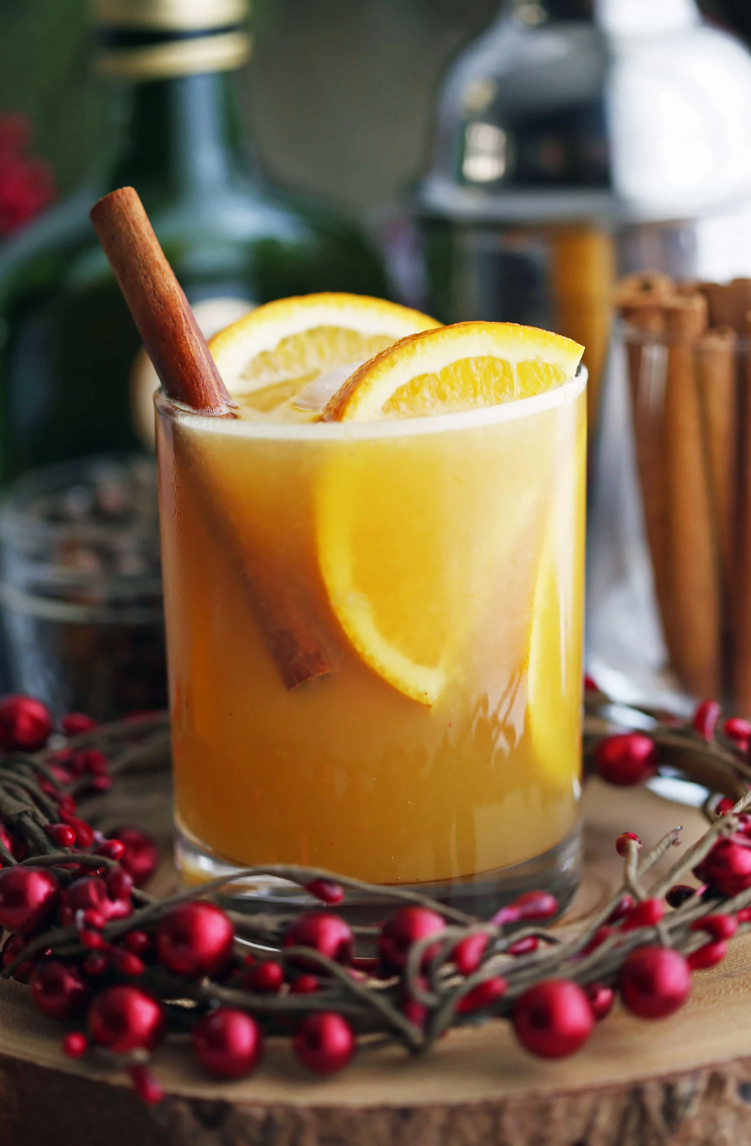 Spiced orange brandy spritzer drink with orange slices and a cinnamon stick in a double old fashioned glass.