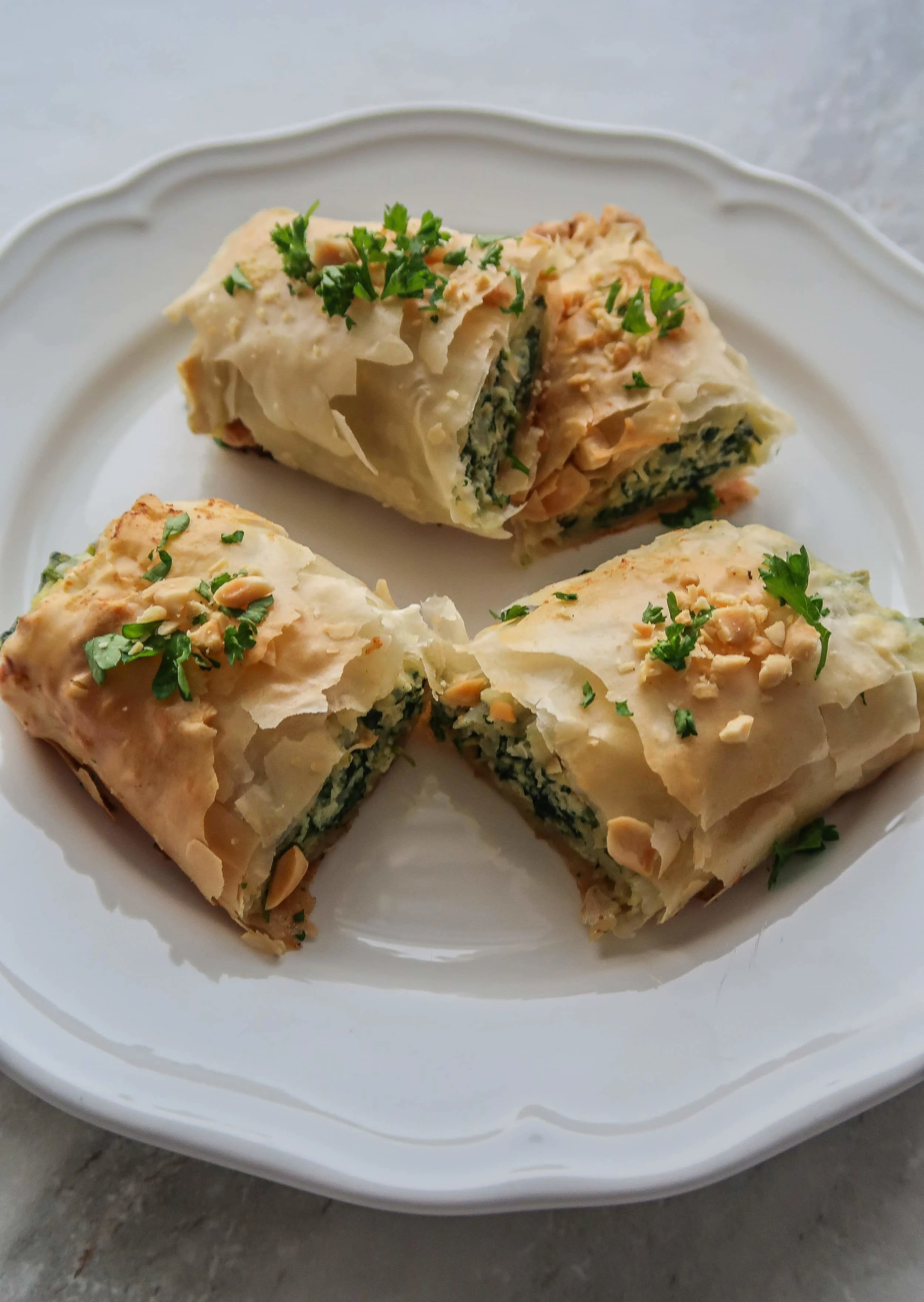 A plate with four Spinach and Ricotta Spanakopita Roll halves.