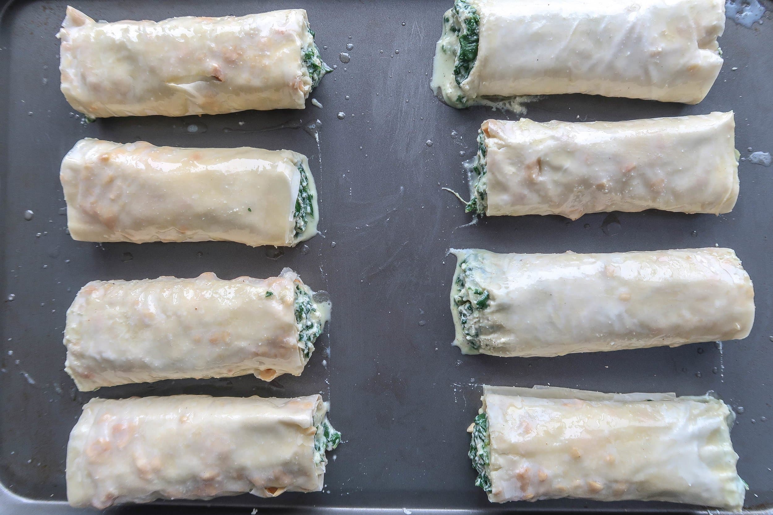 Spanakopita rolls on a baking sheet.