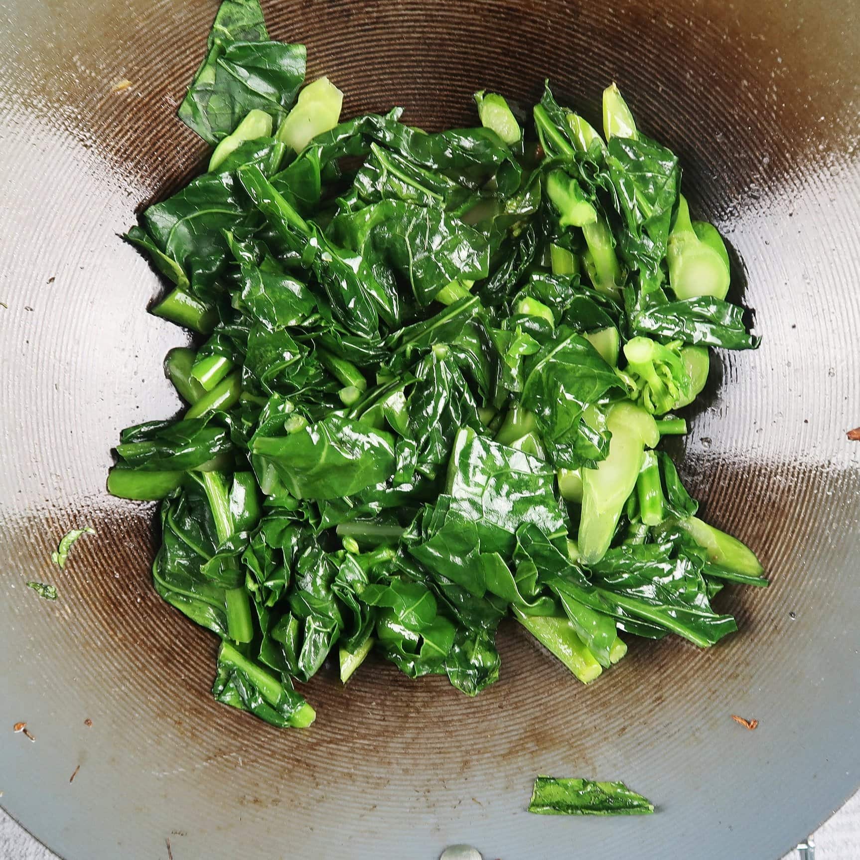 Sauteed sliced gai lan (Chinese broccoli) in the wok.