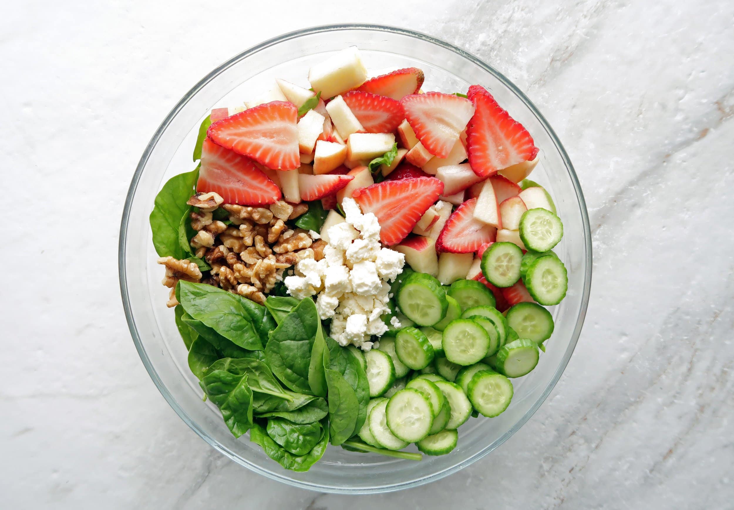 Strawberry Cucumber Spinach Salad with feta and walnuts in a large glass bowl. 