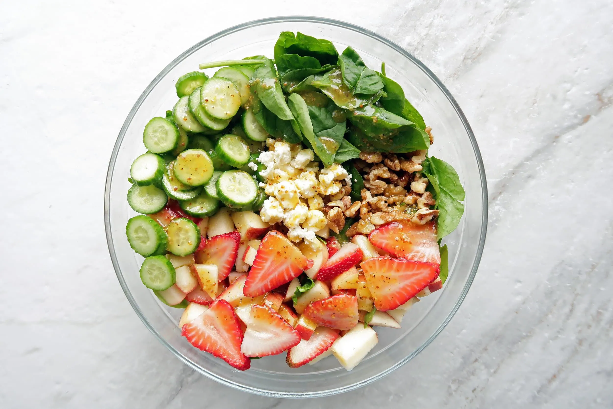 Fresh and healthy Strawberry Cucumber Spinach Salad with Apple Cider Vinaigrette in a large glass bowl.