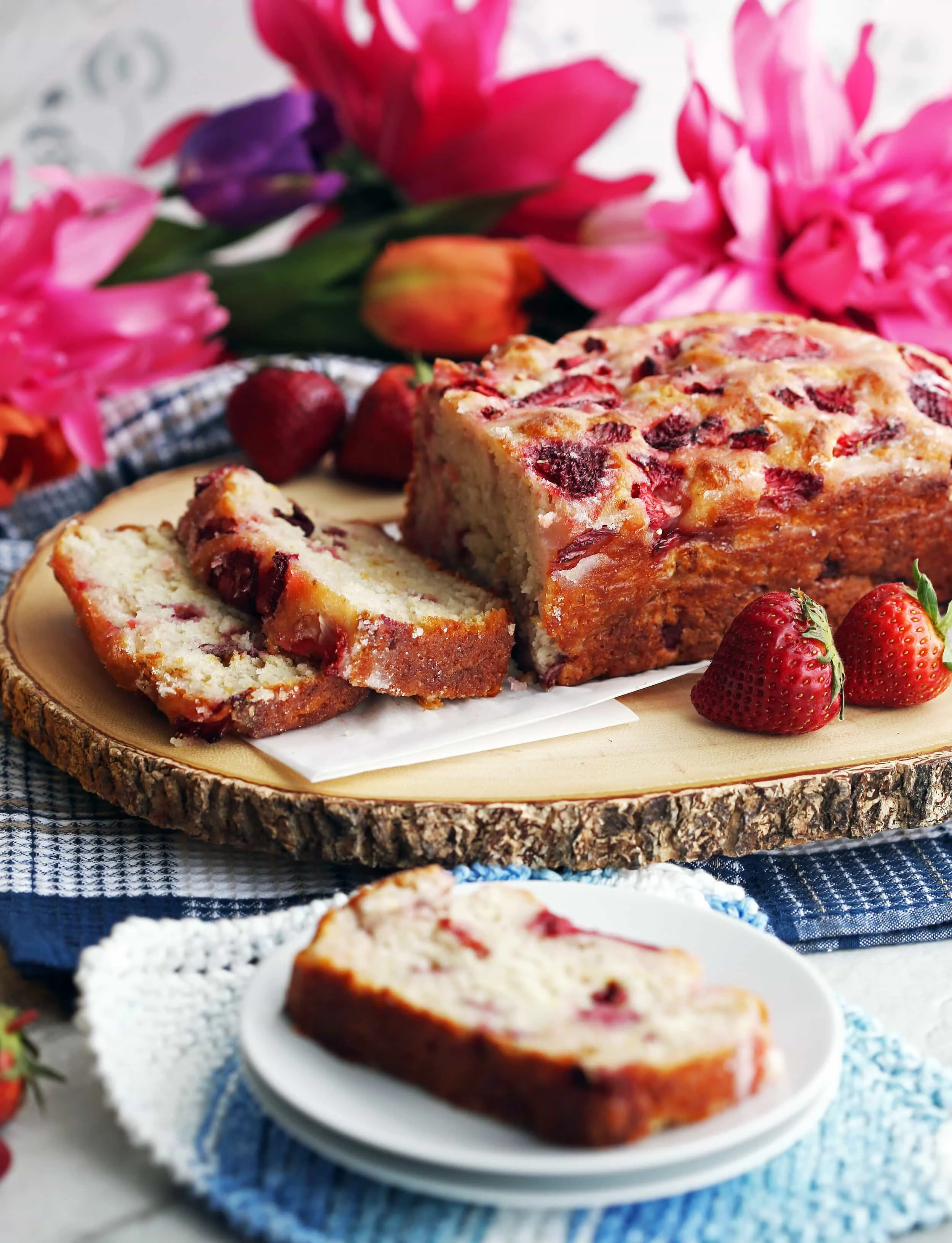 A freshly baked loaf of Strawberry Lemon Yogurt Quick Bread on a large wooden platter.