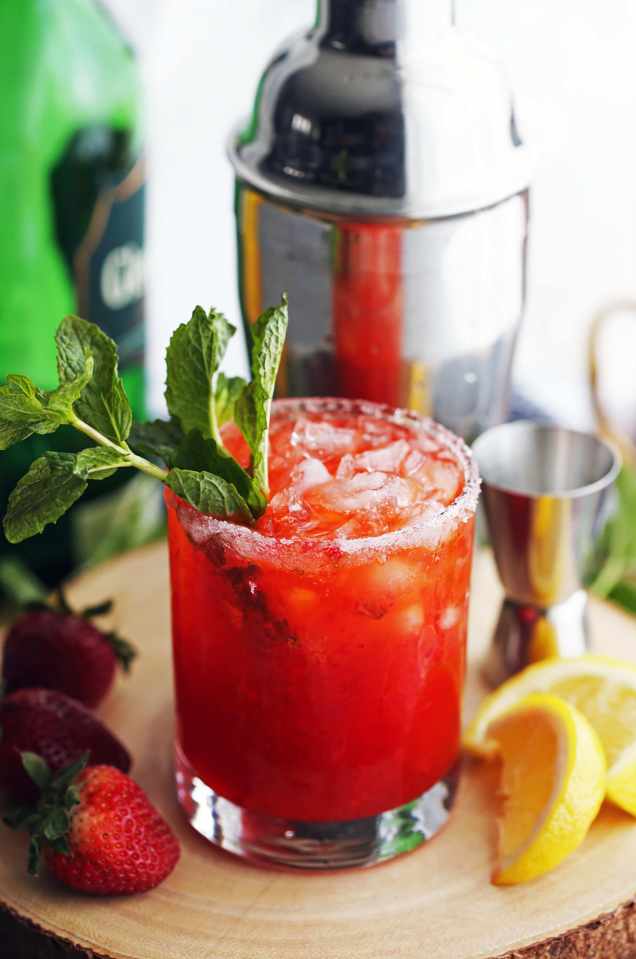 A closeup photo of a Mint Strawberry Whisky Smash Cocktail garnished with a fresh mint sprig.