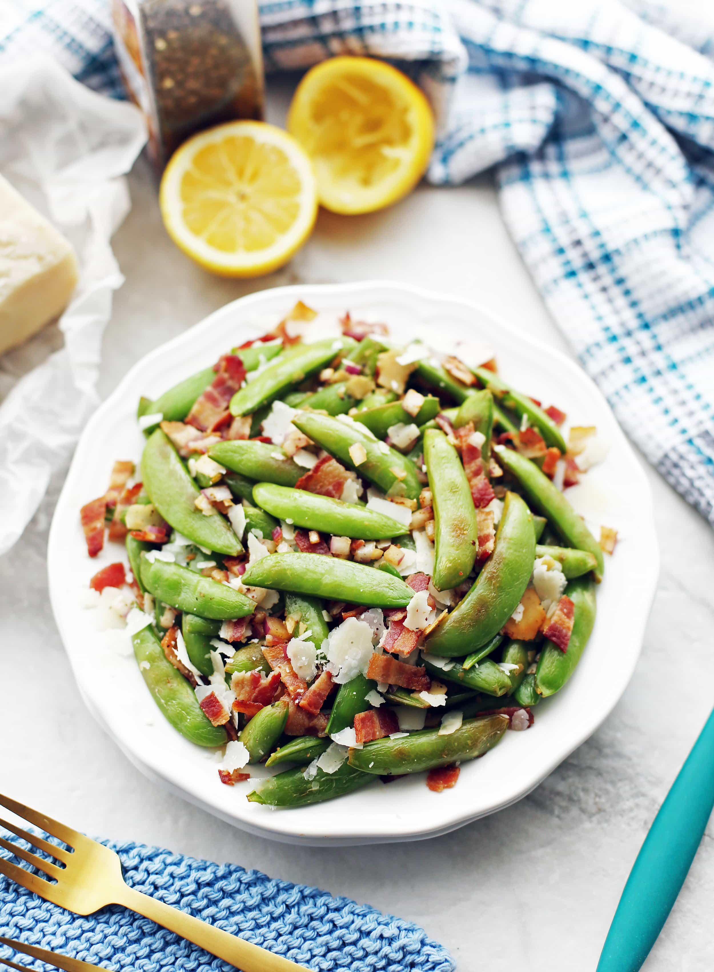 Sugar snap peas with bacon and parmesan piled on a white plate.