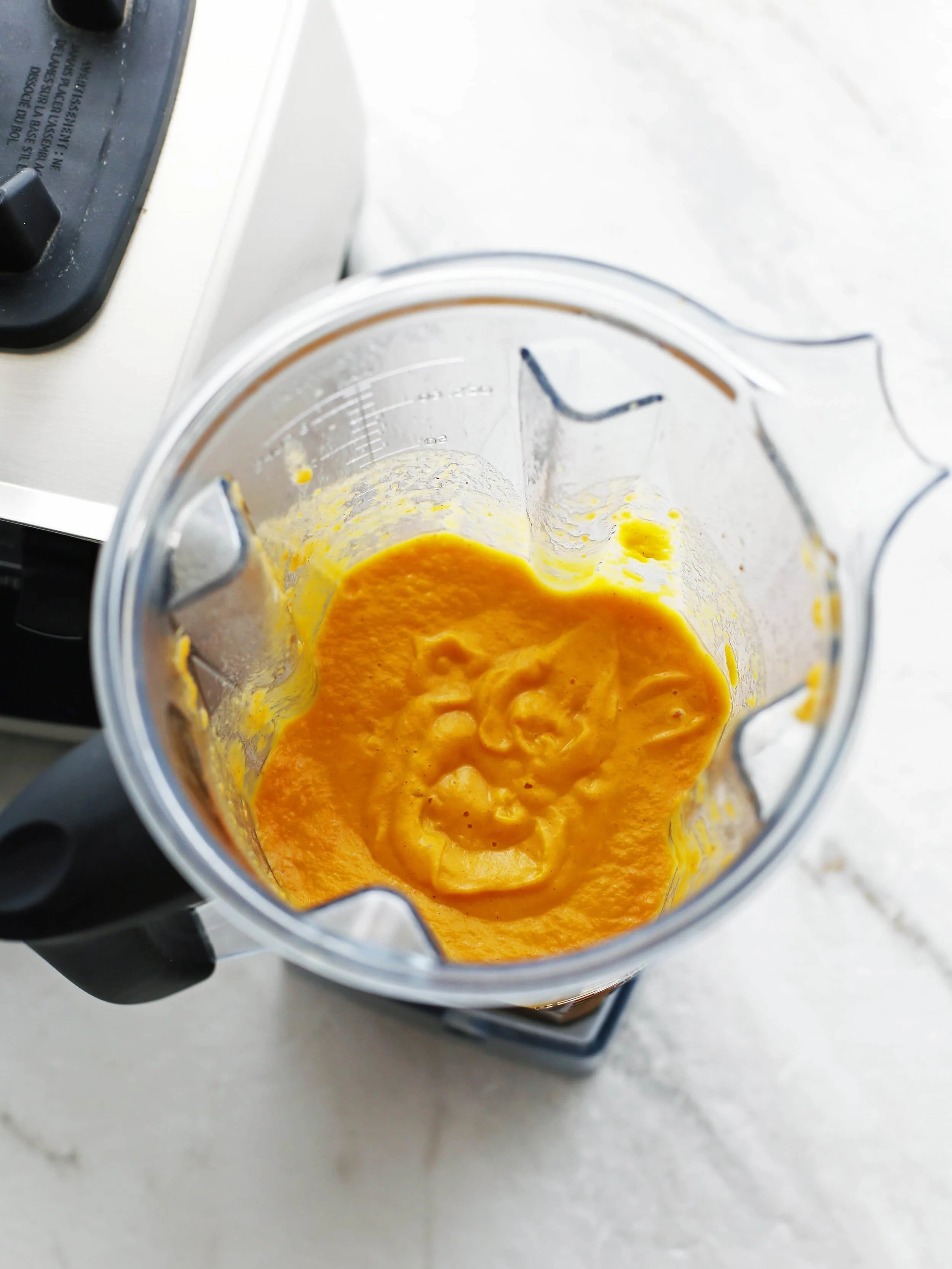 Creamy pureed orange sweet potato coconut soup in a blender.