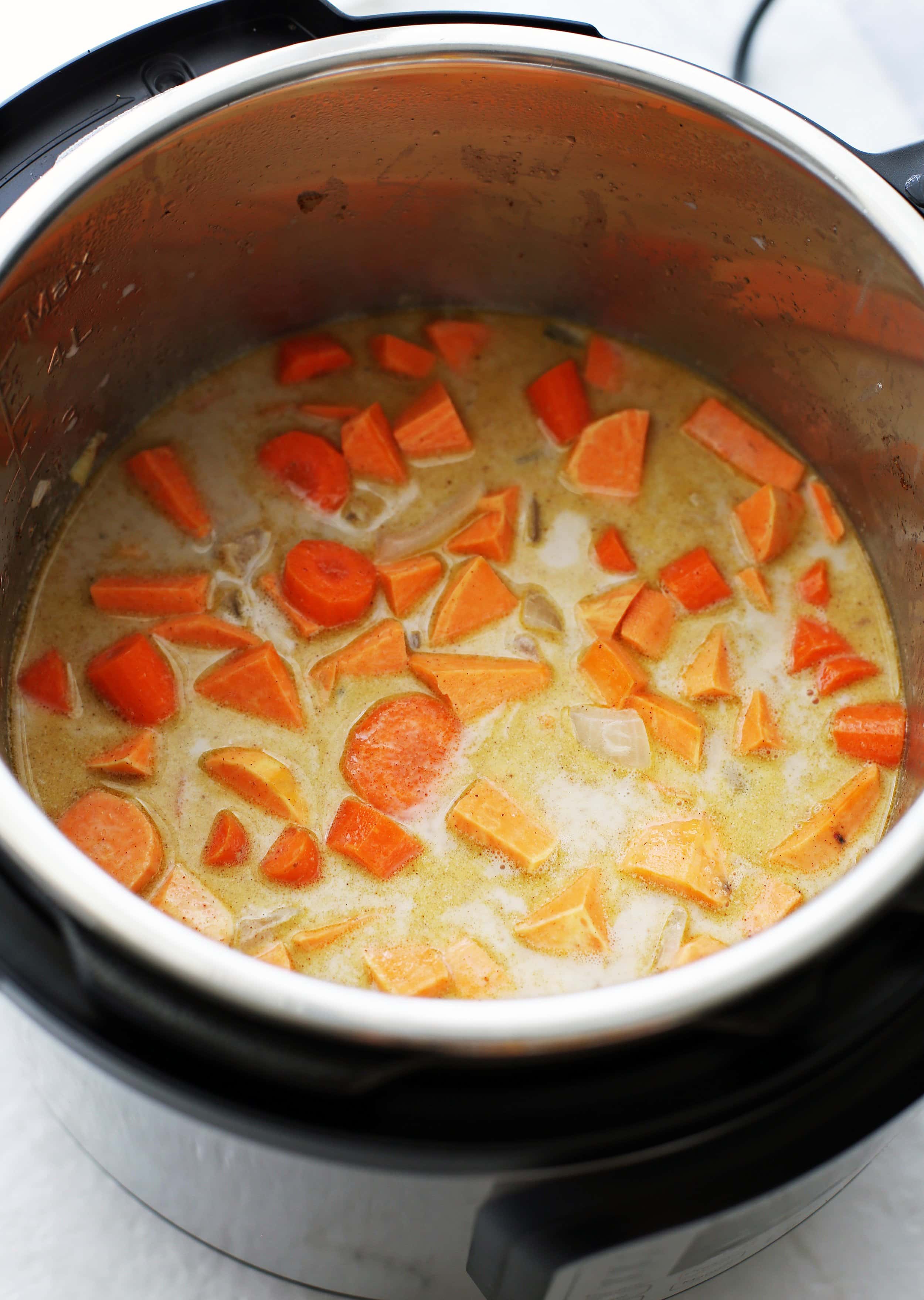 Sautéed onions, garlic, ginger, sweet potato, carrots, coconut milk, and spices in an Instant Pot.