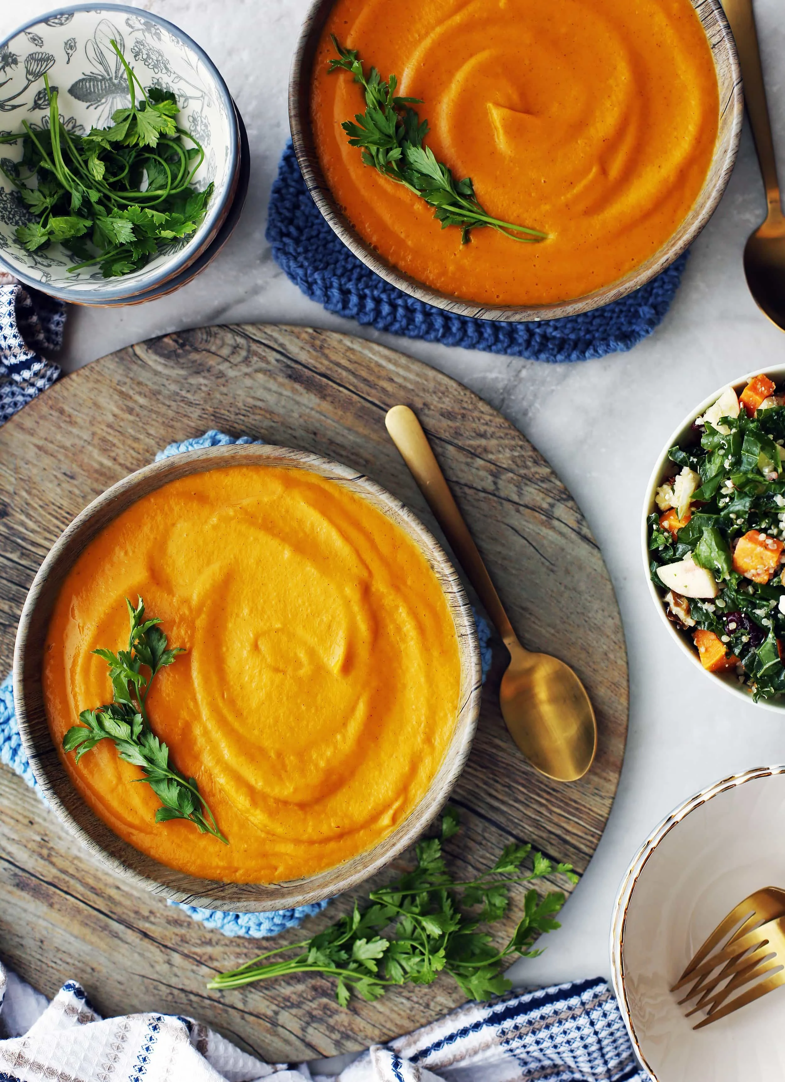 An overhead view of two wooden bowl filled with sweet potato carrot coconut soup with parsley garnish.