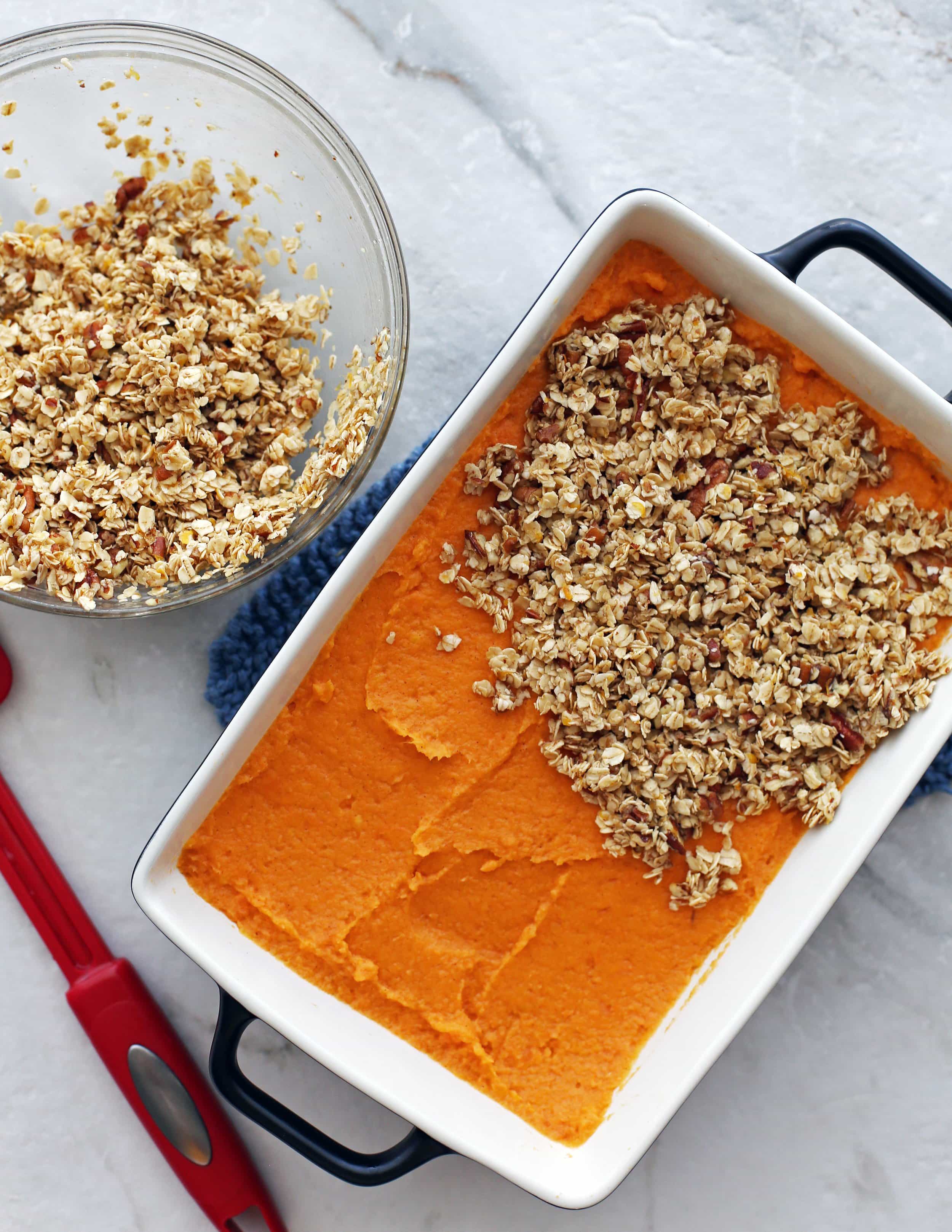 Sweet potato mash in a casserole dish that’s topped halfway with oat topping.