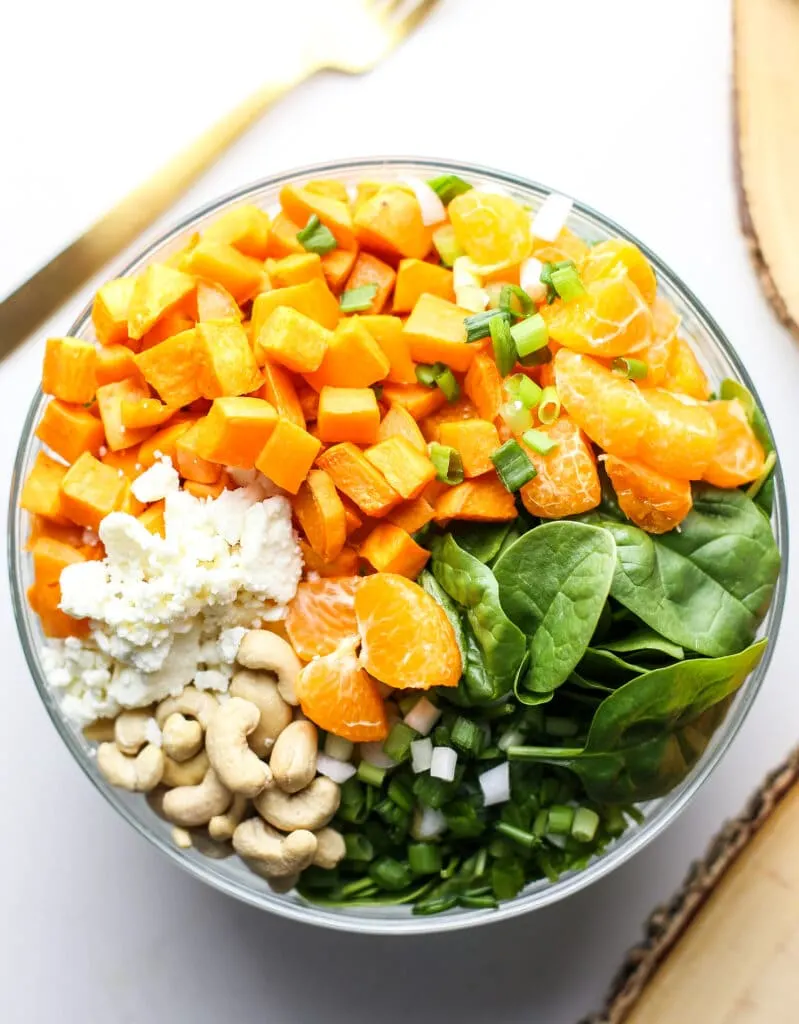 Overhead view of sweet potato salad ingredients in a glass bowl.