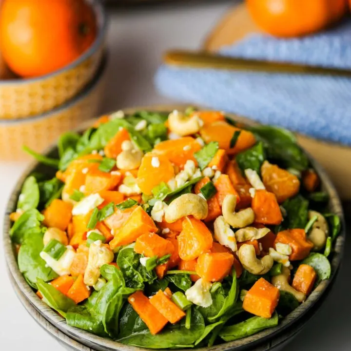 Sweet potato orange spinach salad in a wooden bowl.