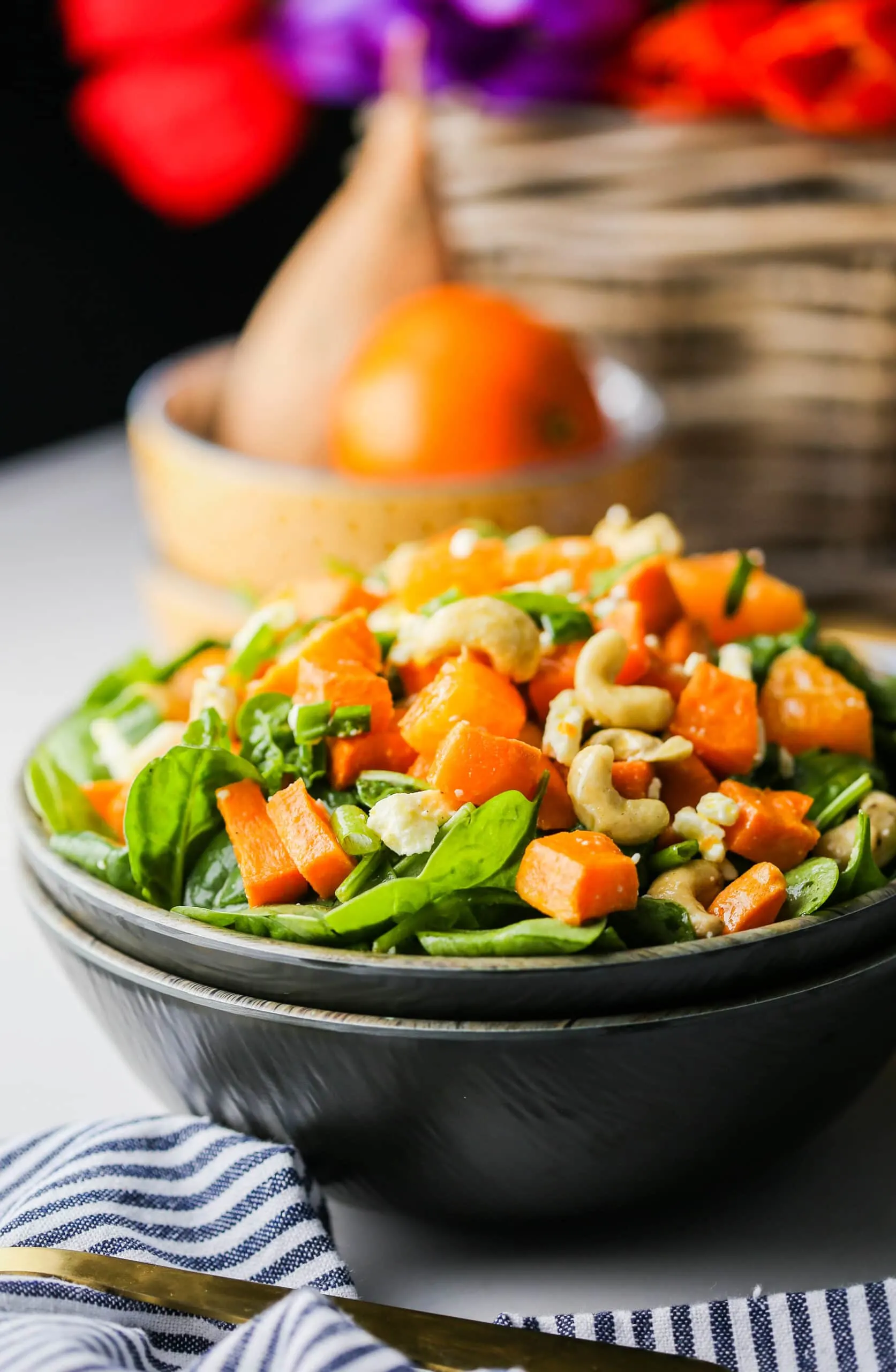 Side view of sweet potato orange spinach salad in a wooden bowl.