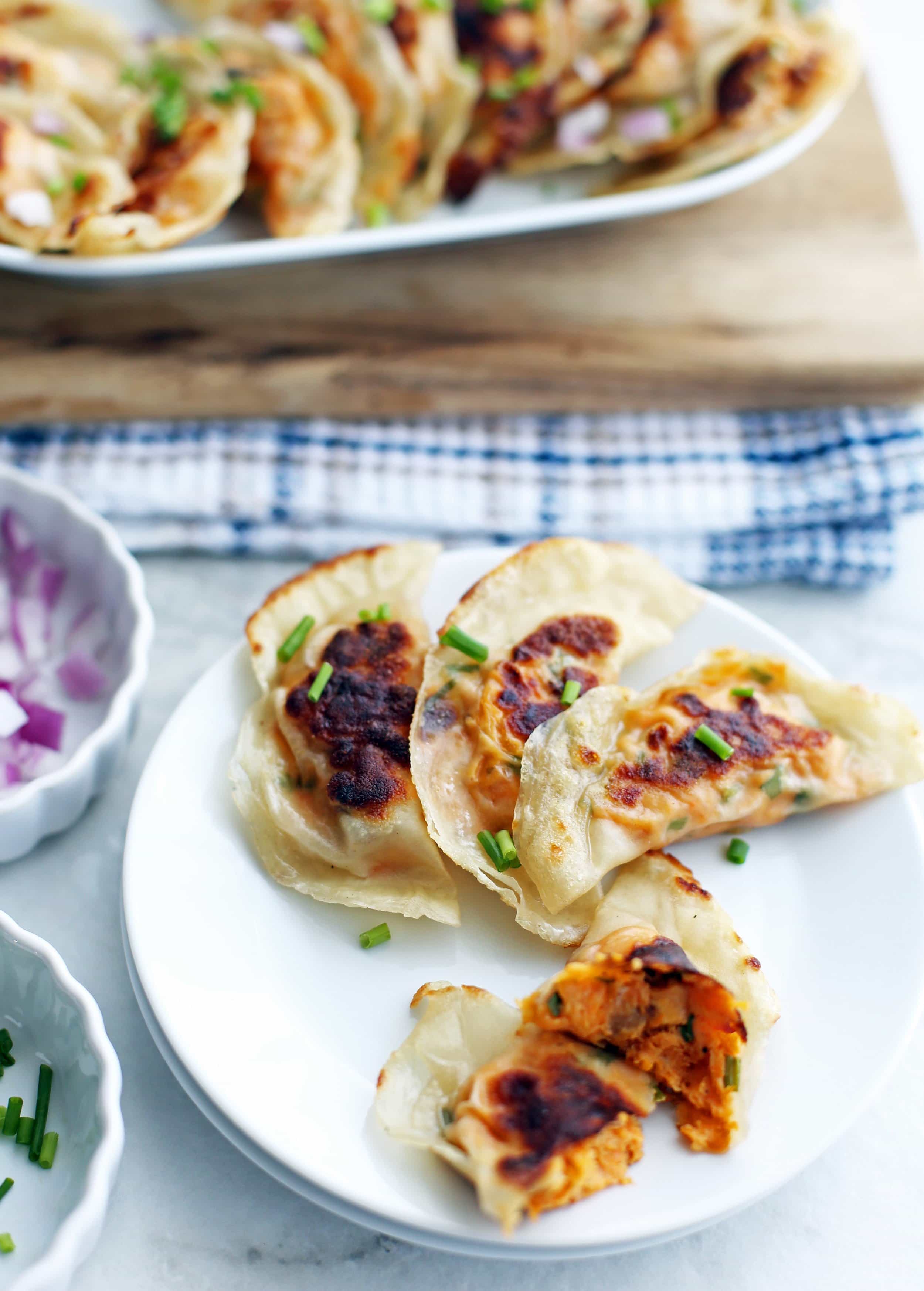 A close-up plate of sweet potato cream cheese potstickers with one cut in half.