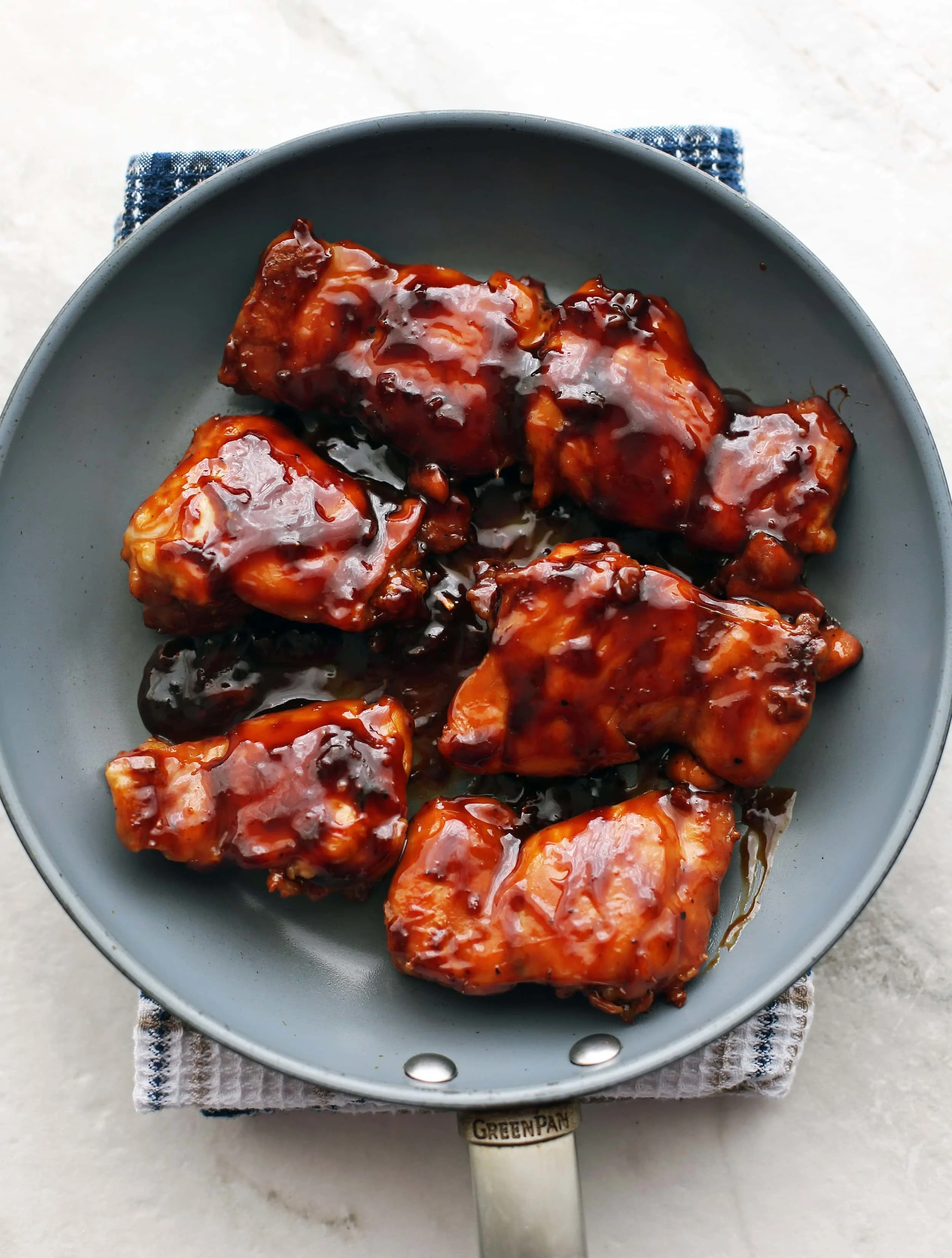 Six pan-cooked chicken thighs covered with teriyaki sauce in a skillet.