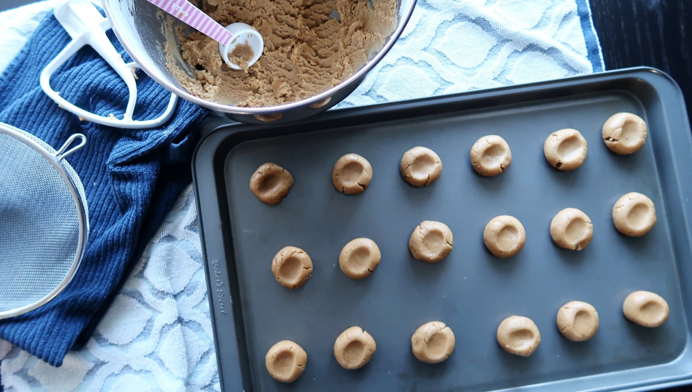 Thumbprint cookie dough on a baking sheet.