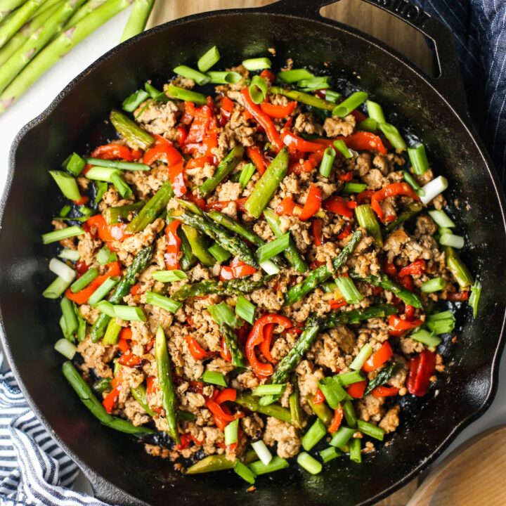 Overhead view of a stir-fry featuring ground turkey, asparagus, and bell pepper in a cast iron skillet.