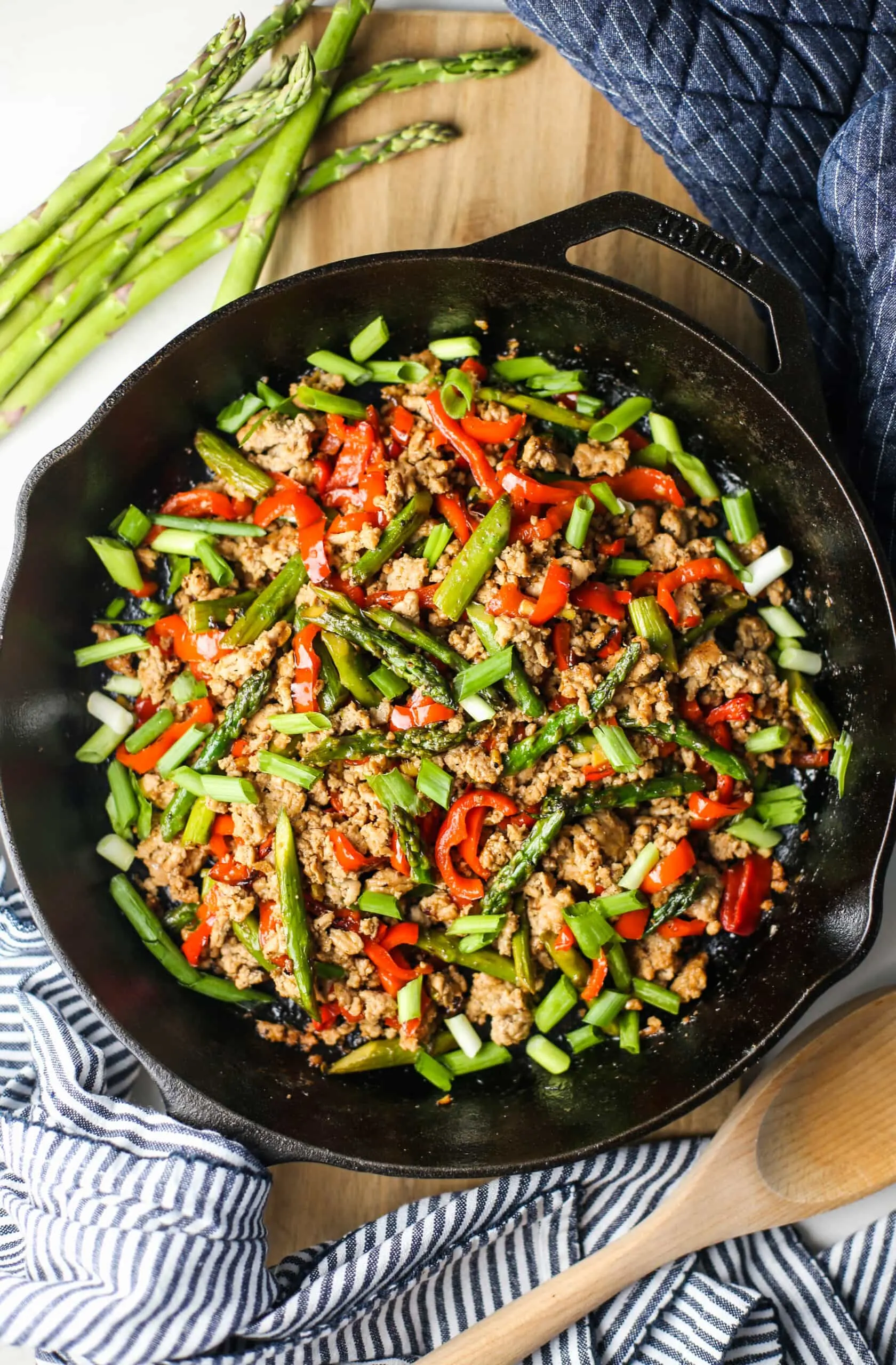 Overhead view of a stir-fry featuring ground turkey, asparagus, and bell pepper in a cast iron skillet.