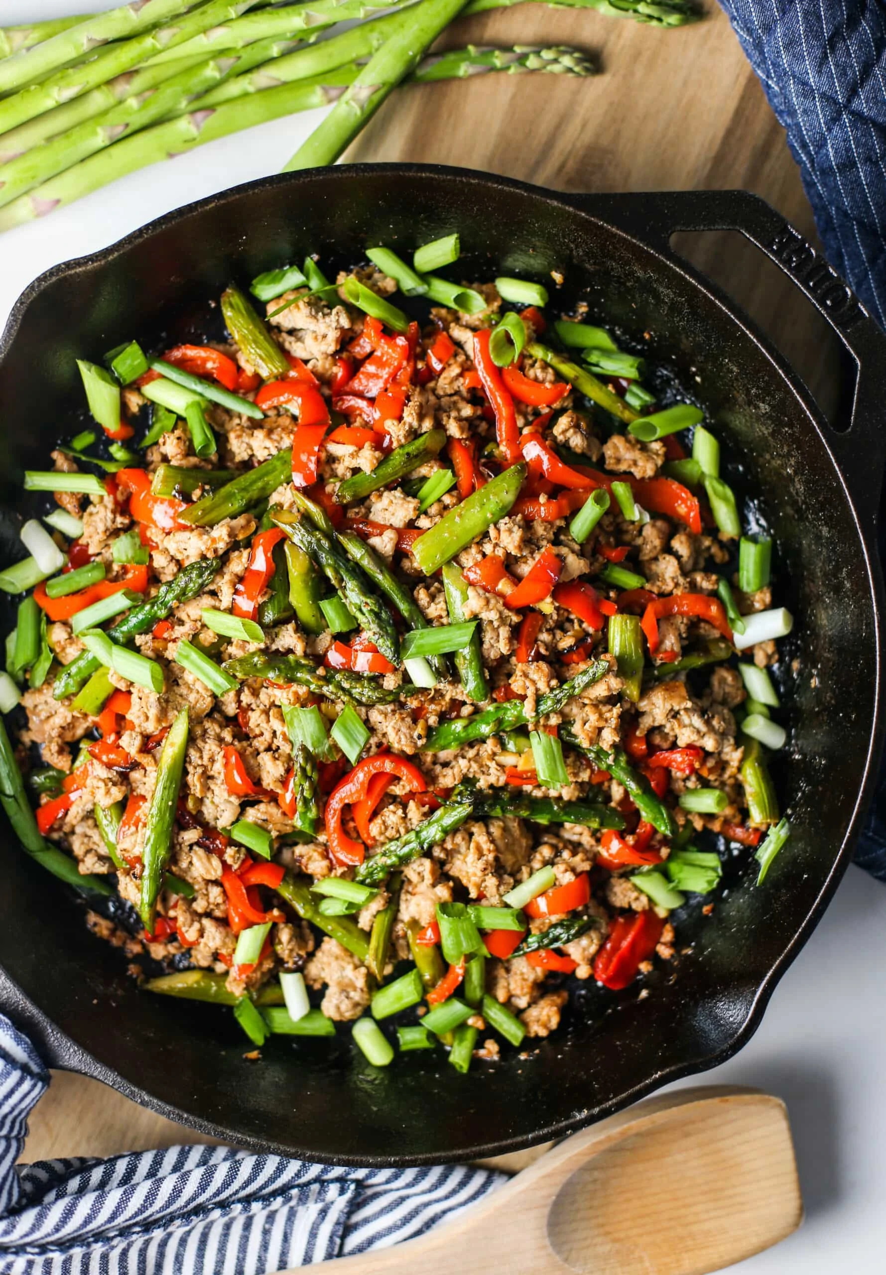 Overhead view of cast iron skillet containing a ground turkey and asparagus stir-fry.