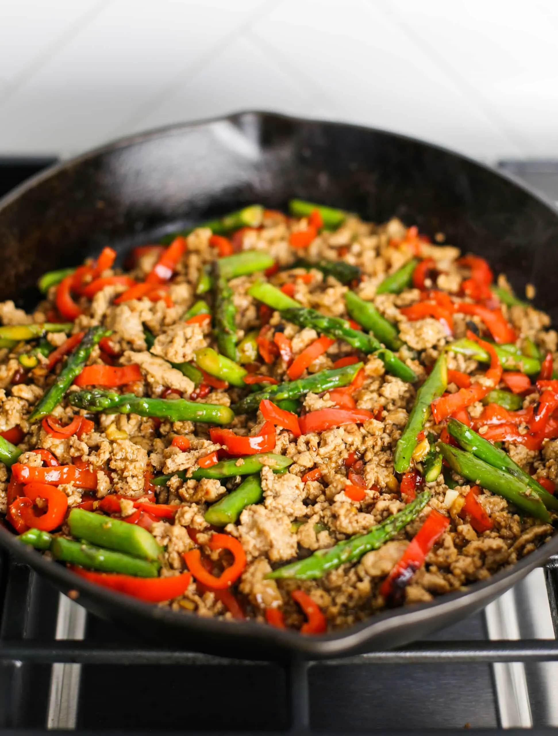 Stir-fried ground turkey, asparagus, and bell pepper in a cast iron skillet.