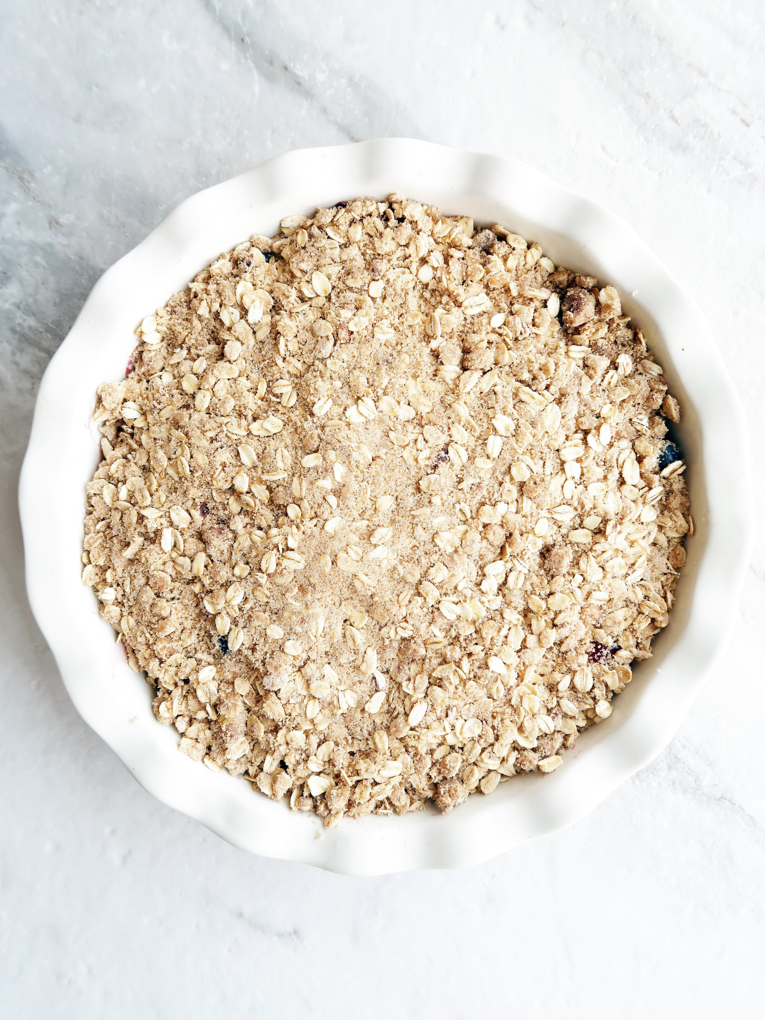 In a pie dish, blueberries and cherries with rolled oat topping spread on top