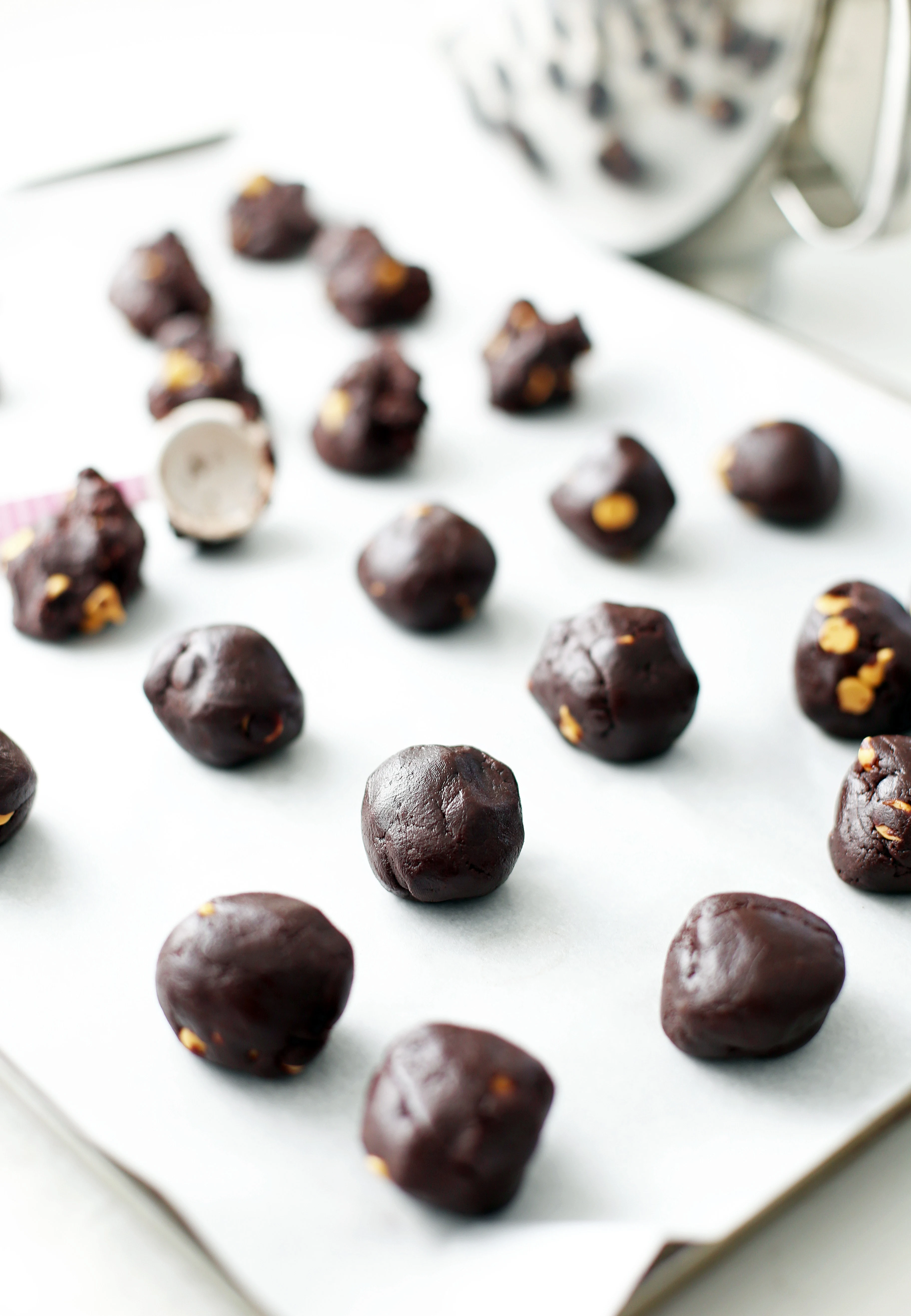 Scooped and rolled chocolate butterscotch chip cookie batter on a baking sheet.