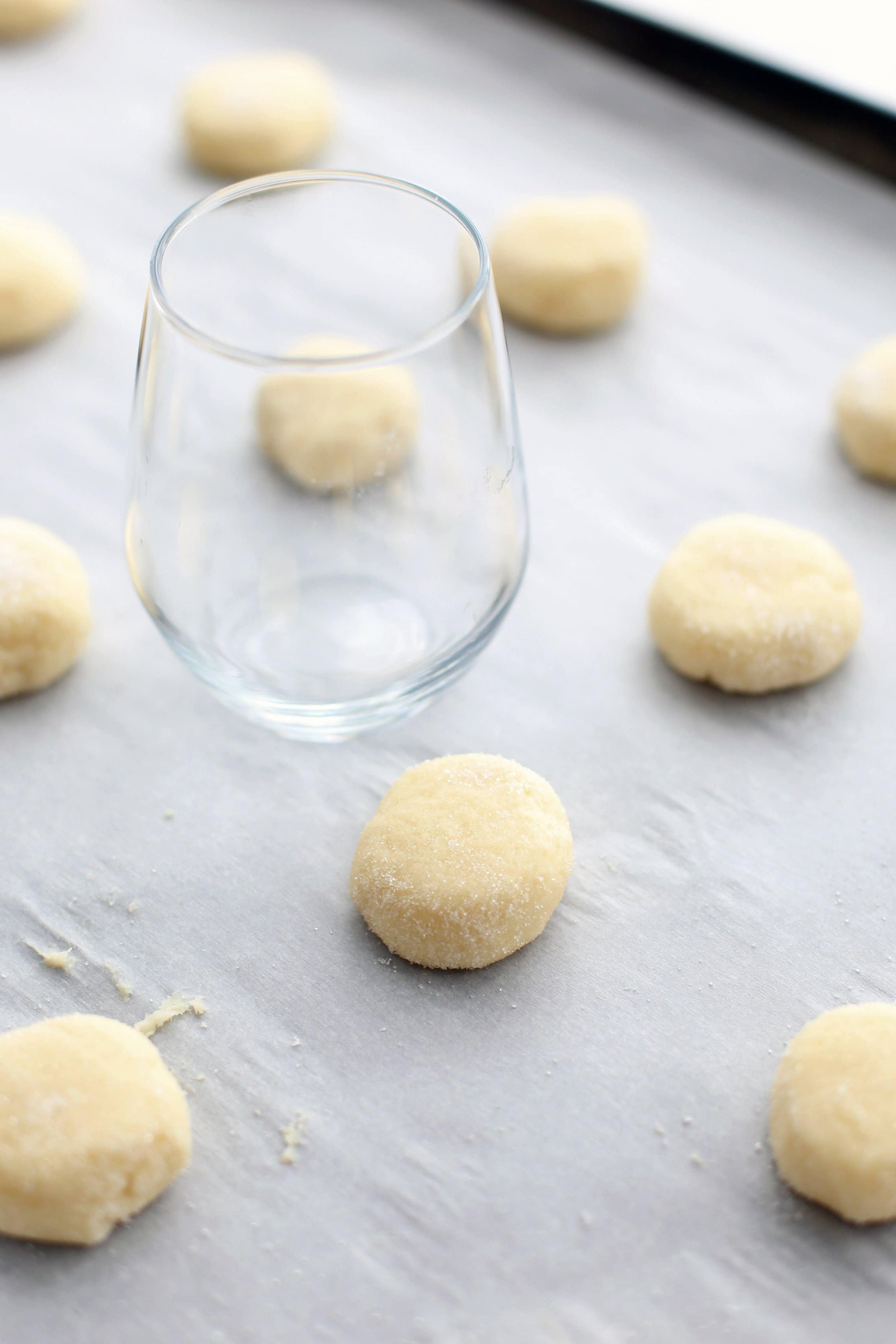 Unbaked cream cheese cookies on a parchment paper-lined baking sheet.