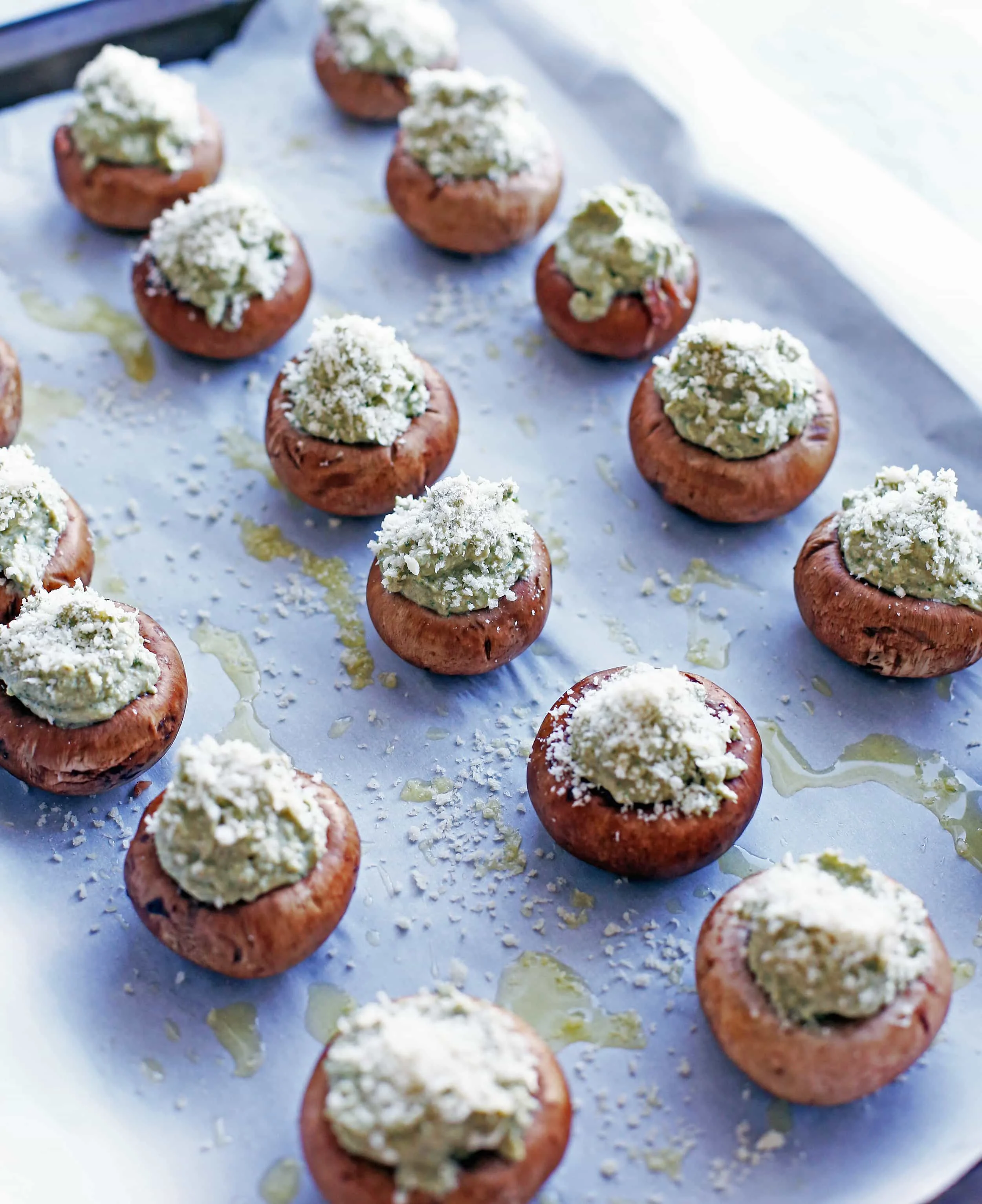 Stuffed cheese mushrooms with breadcrumb topping on a baking sheet ready to be baked.