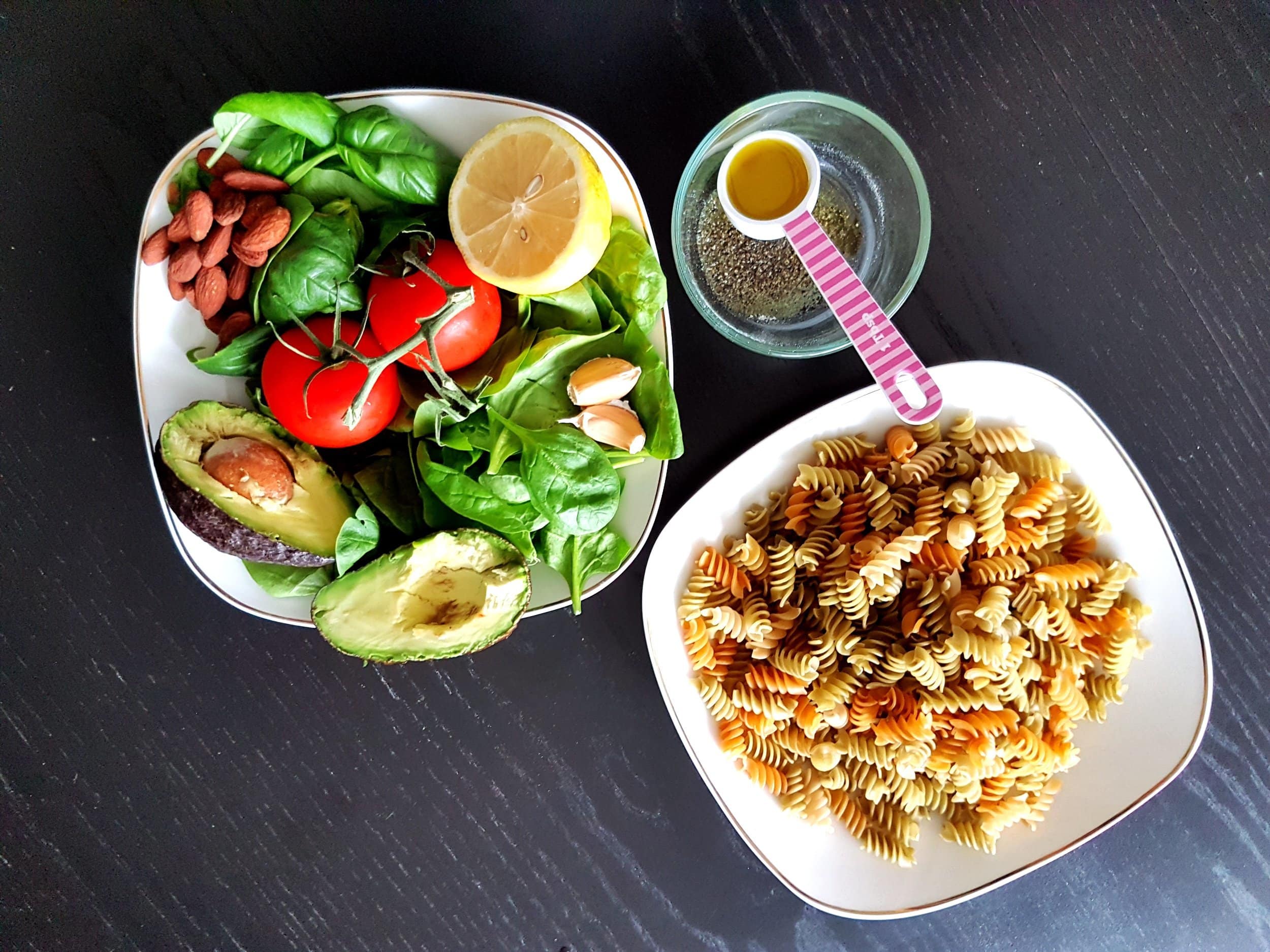 Basil, tomatoes, avocado, pasta, a lemon, almonds, and garlic.