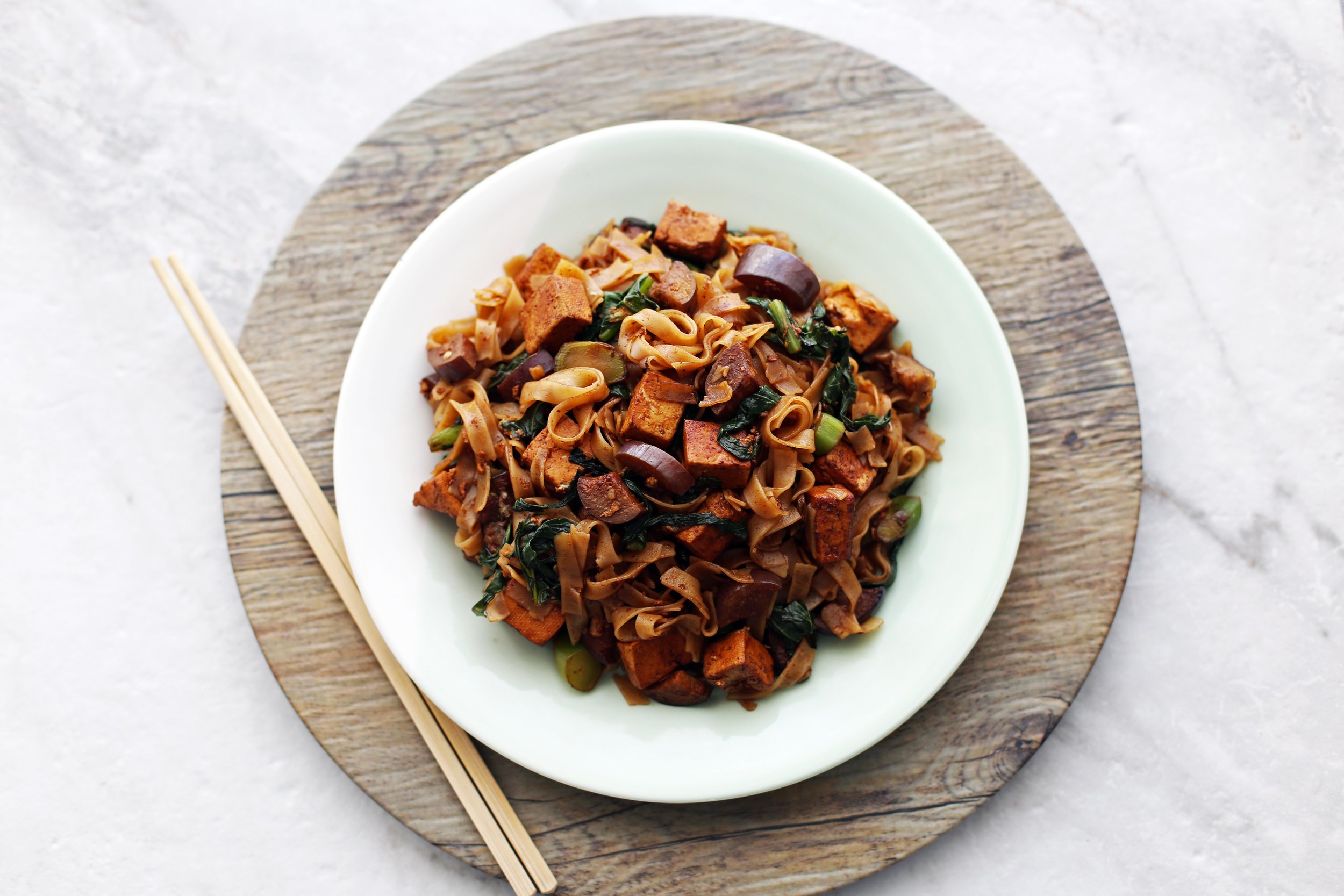 a plate of Vegetarian Pad See Ew topped with Thai basil, ready to eat 