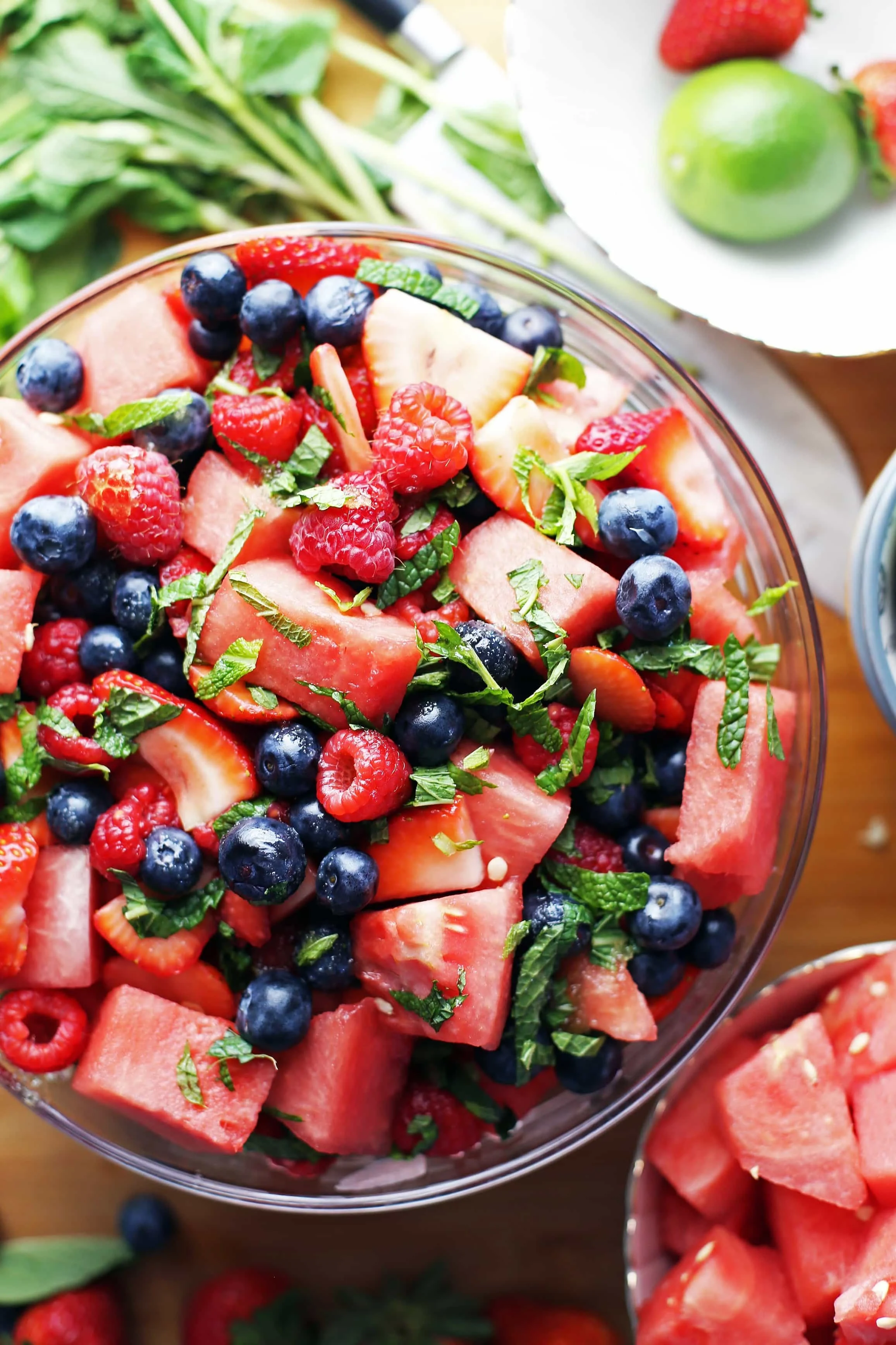 Top down view of watermelon berry summer salad in a glass bowl and a small bowl full of watermelon chunks.