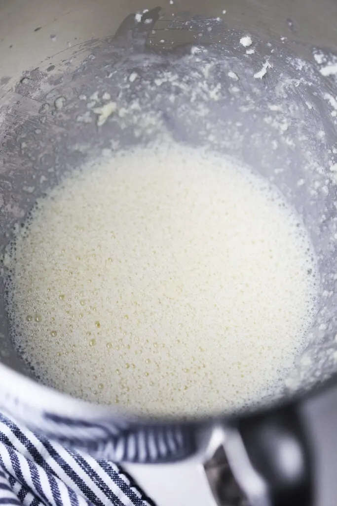 Creamed butter and sugar mixed with egg and milk in a large stainless steel bowl.