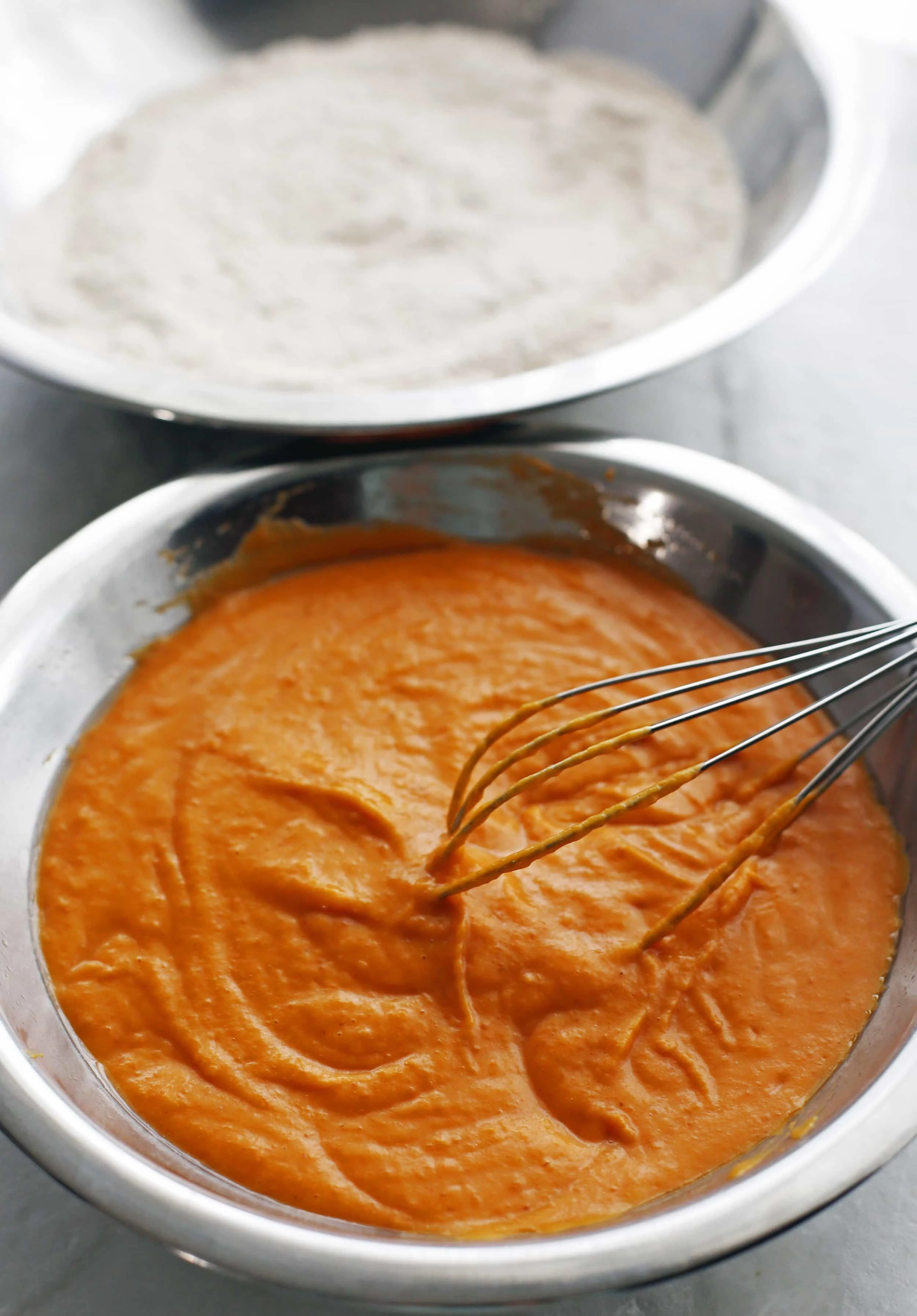 A metal bowl containing pumpkin puree, vegetable oil, and eggs mixed together.