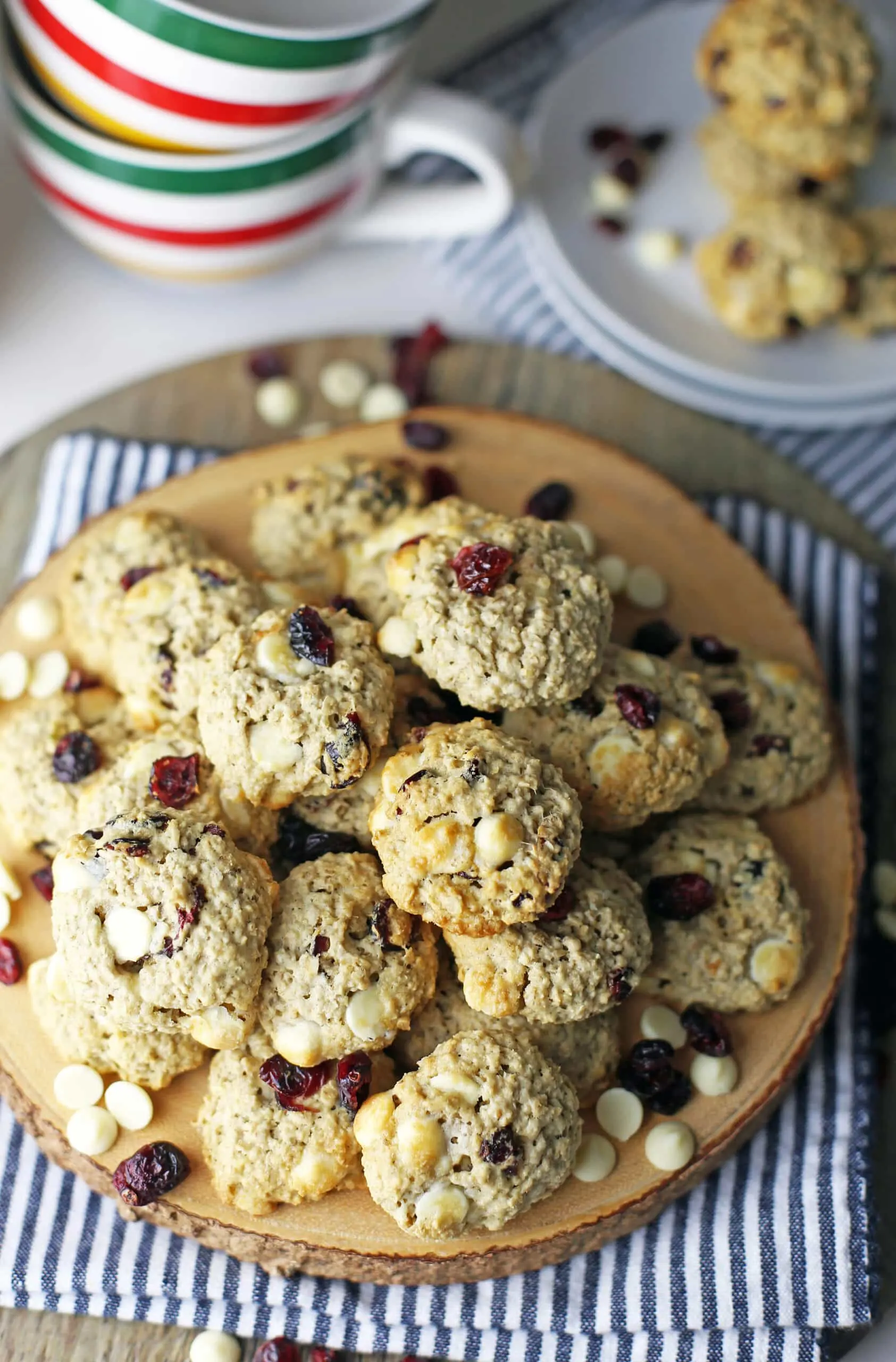 Overhead view of a round wooden platter piled high with white chocolate cranberry oatmeal cookies.