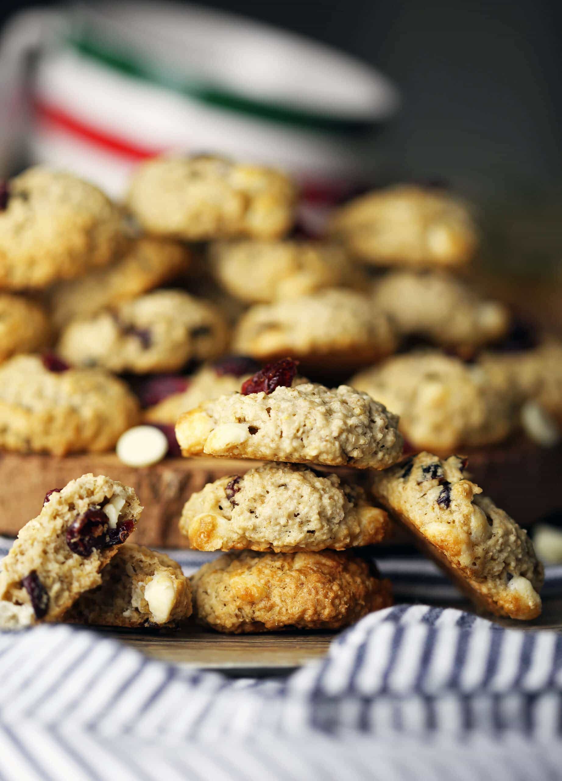 White chocolate cranberry oatmeal cookies piled on a plate and in on a wooden platter.