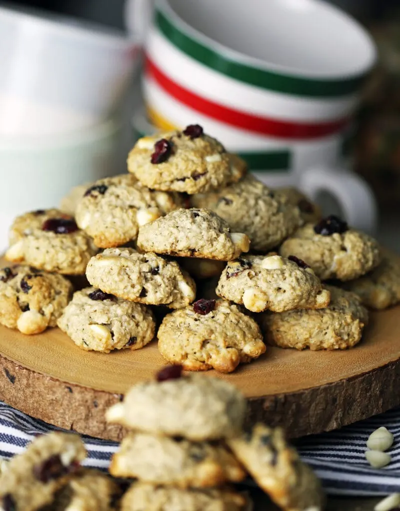 White chocolate cranberry oatmeal cookies piled on each other on a round wooden platter.