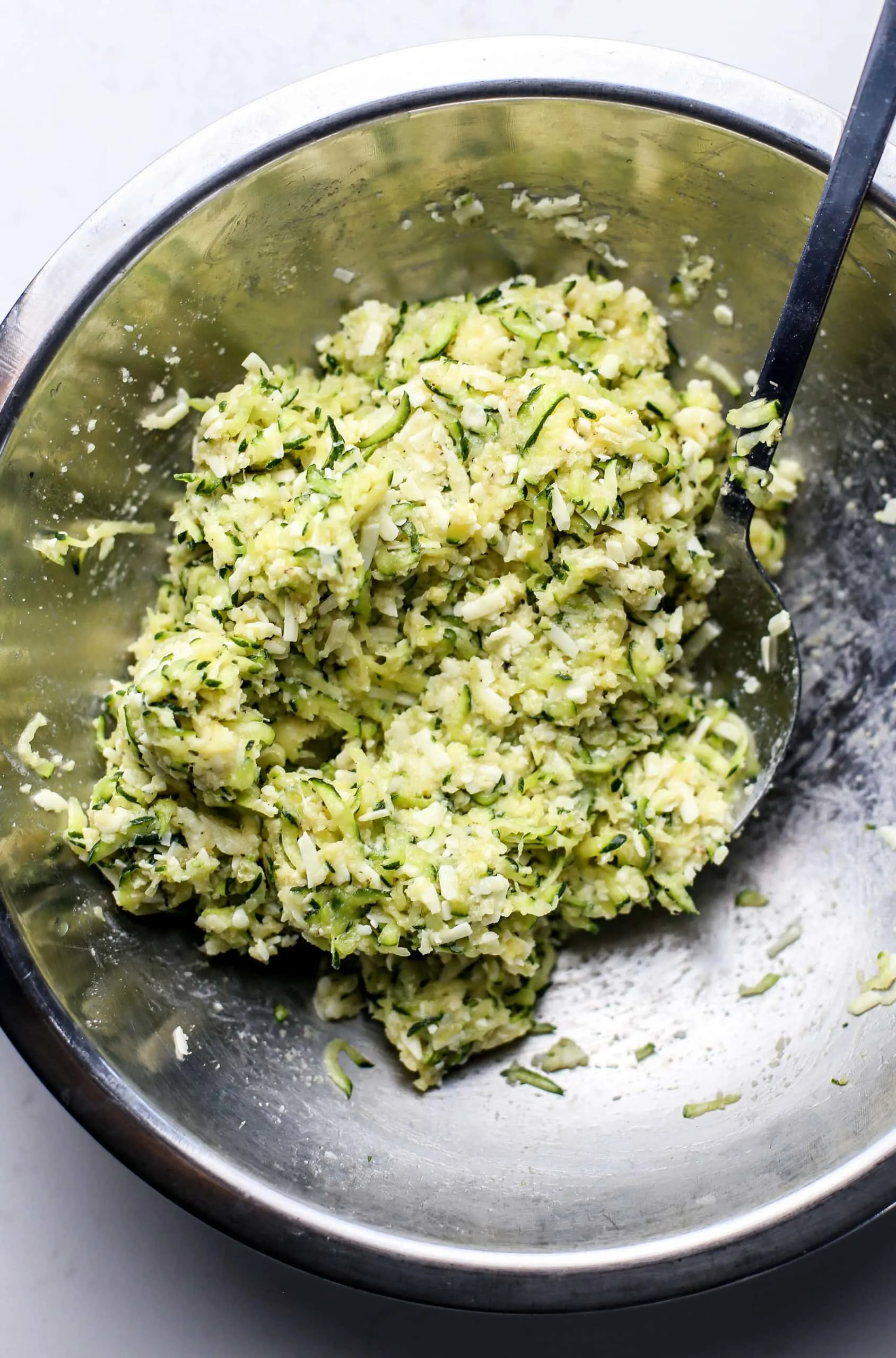 Zucchini bite ingredients combined together in a stainless steel bowl.