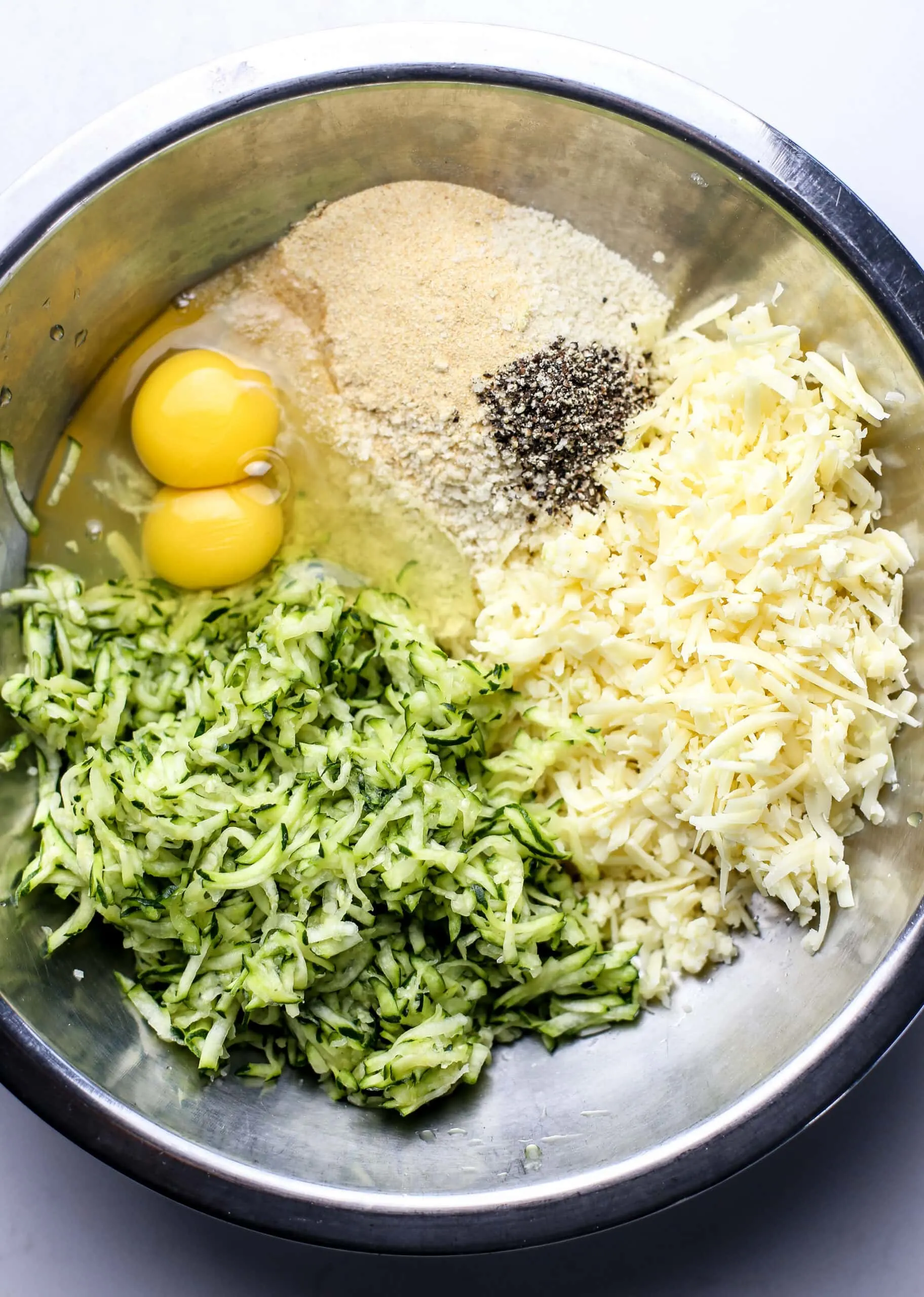 Zucchini bite ingredients in a stainless steel bowl.