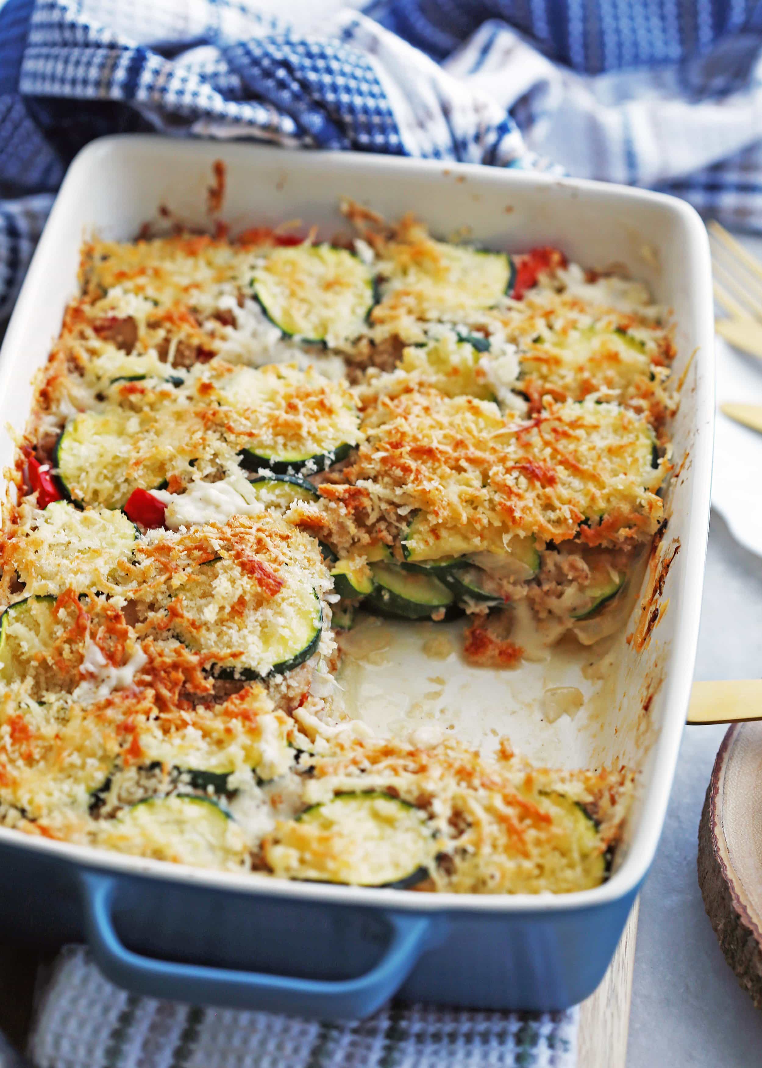 Zucchini Gratin with Gruyère and Panko Breadcrumbs in a blue rectangular casserole dish with one piece of gratin removed.