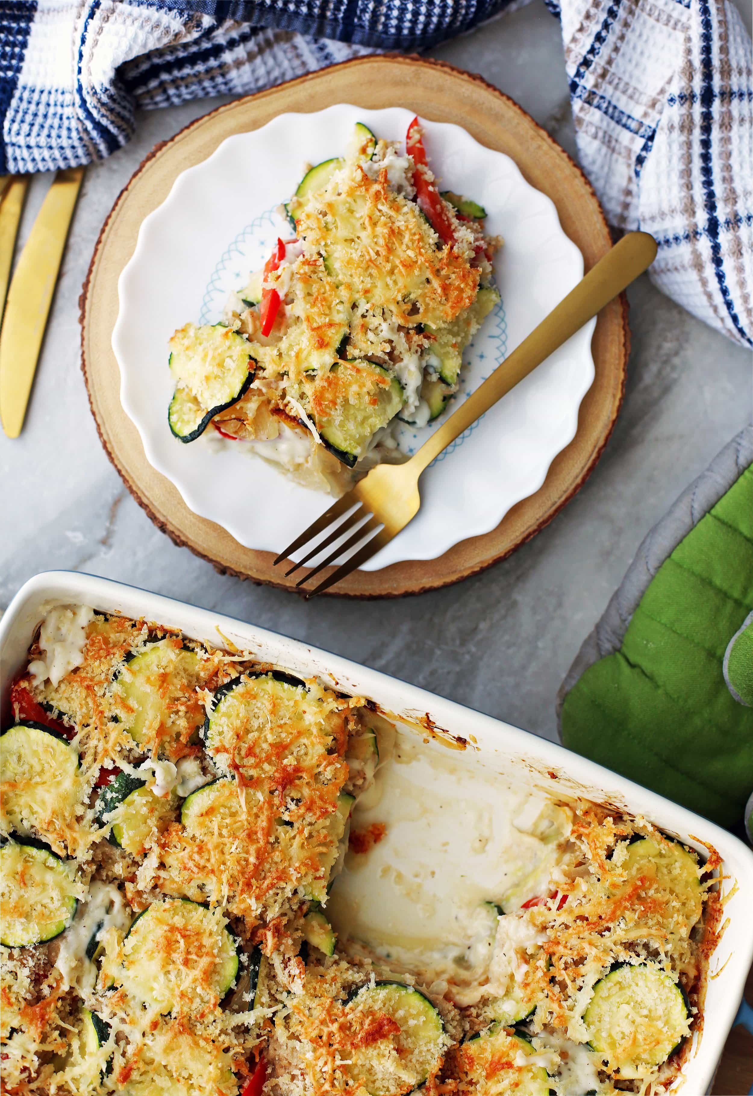 Zucchini Gratin with a crispy Gruyère and Panko Breadcrumb topping in a casserole dish with one piece of gratin on a plate.