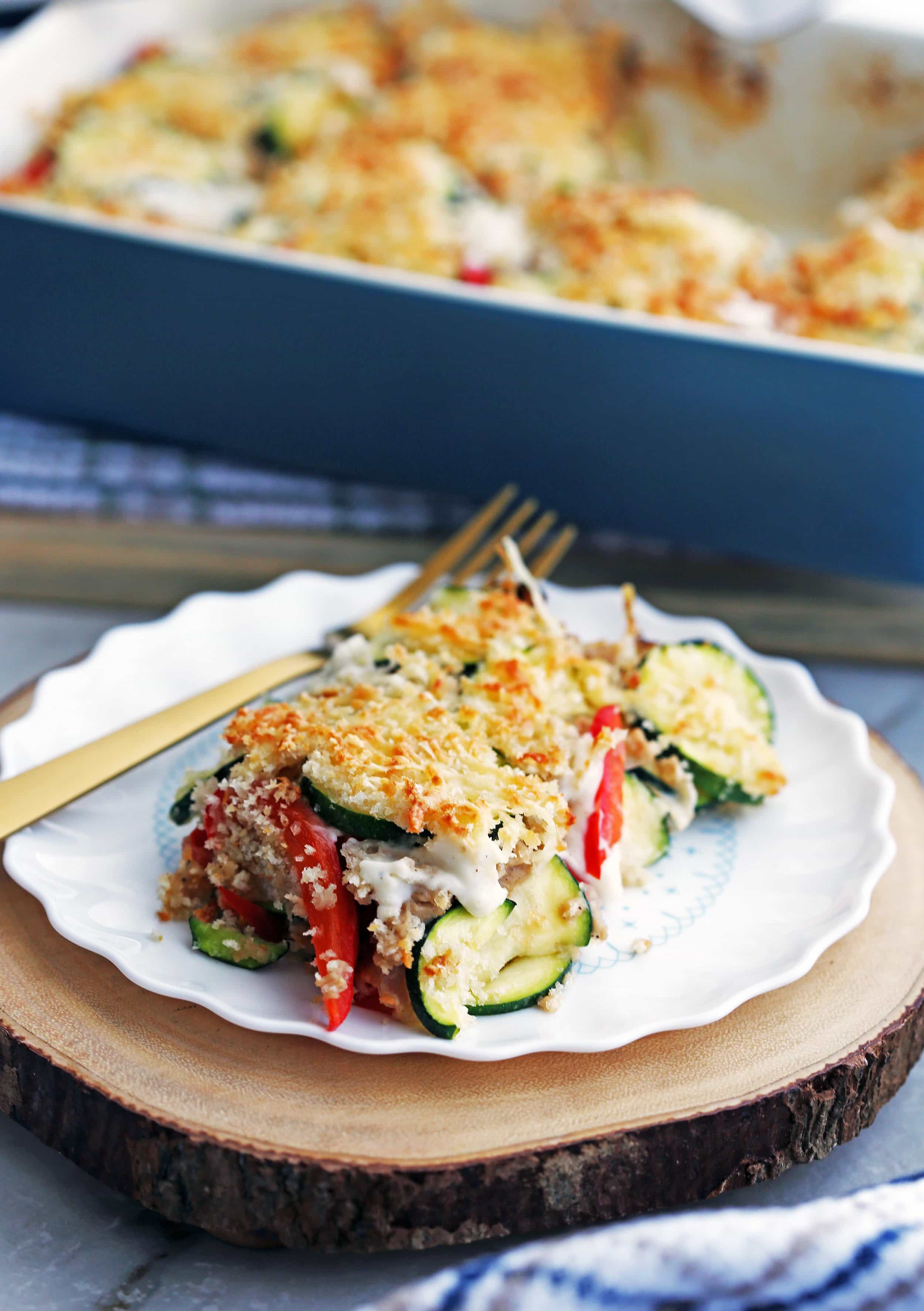 A piece of Zucchini Gratin with Gruyère and Panko Breadcrumbs on a white plate along with a fork.